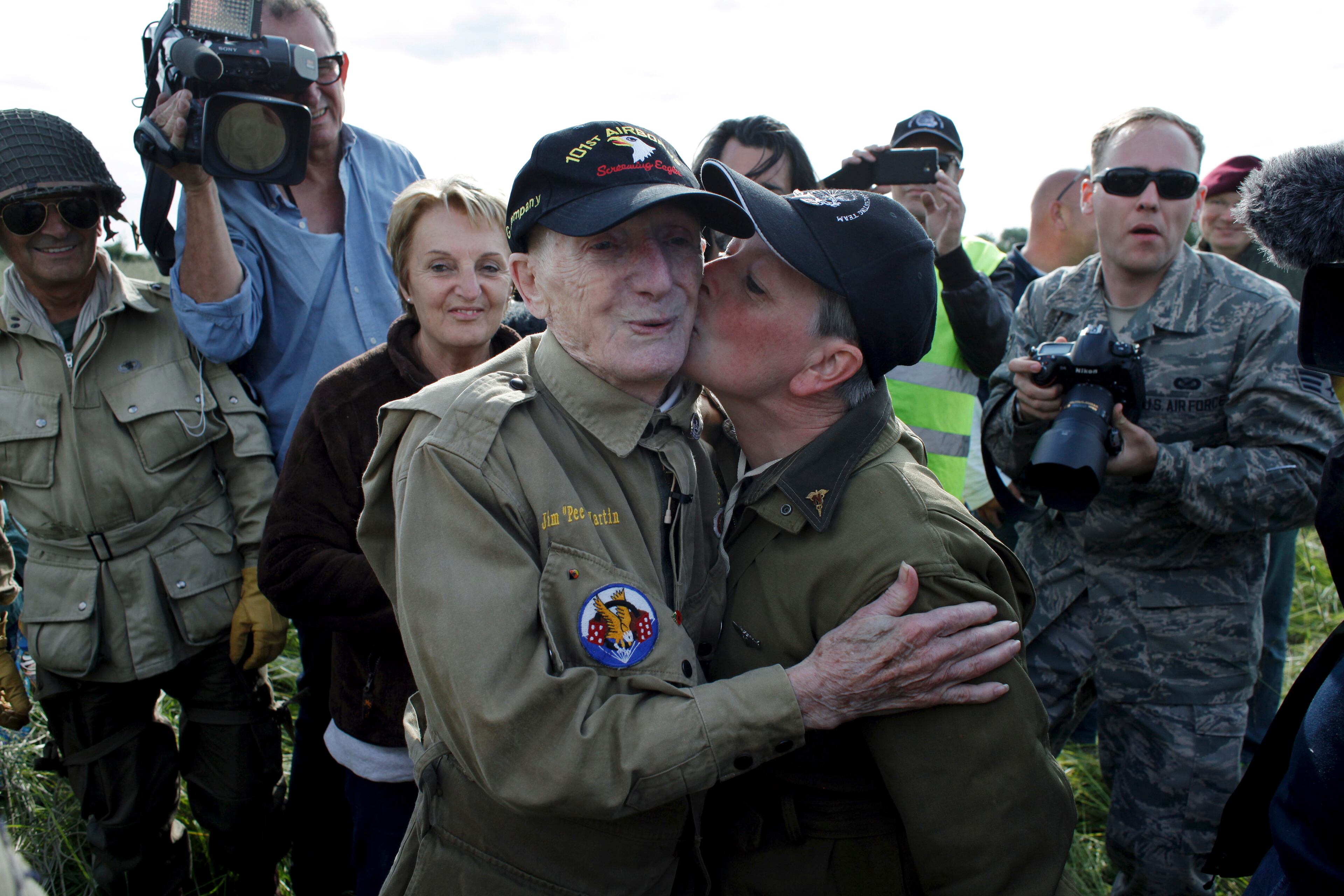 93 year old U.S WW II veteran Jim Martin of the 101st Airborne, is kissed by an unidentified woman after he completed a tandem parachute jump onto Utah Beach, western France, Thursday June 5, 2014, as part of the commemoration of the 70th anniversary of the D Day.