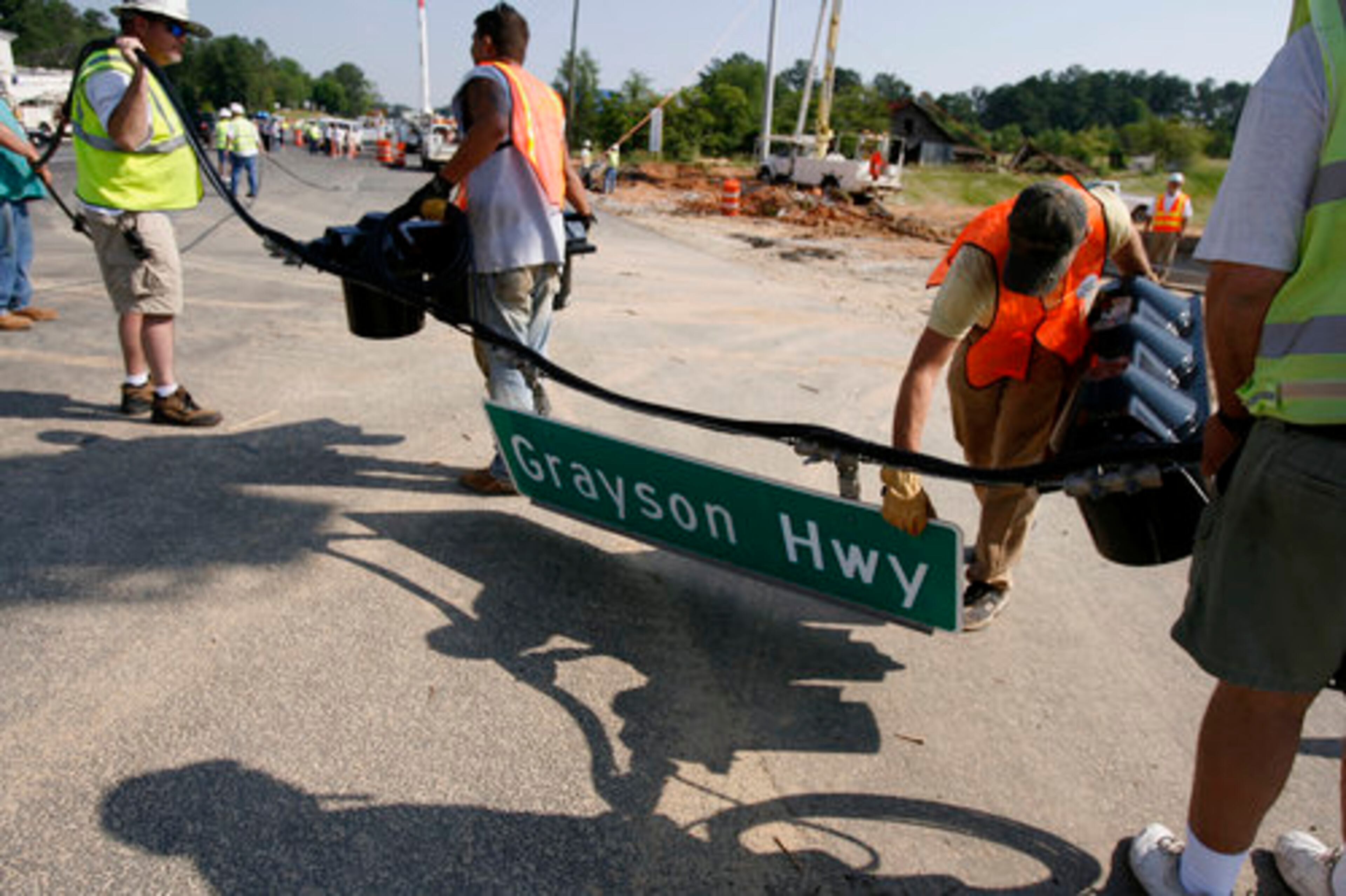 Utility crews remove and reconnect wires and traffic signals while the move of the Adair House progresses along Grayson Highway.