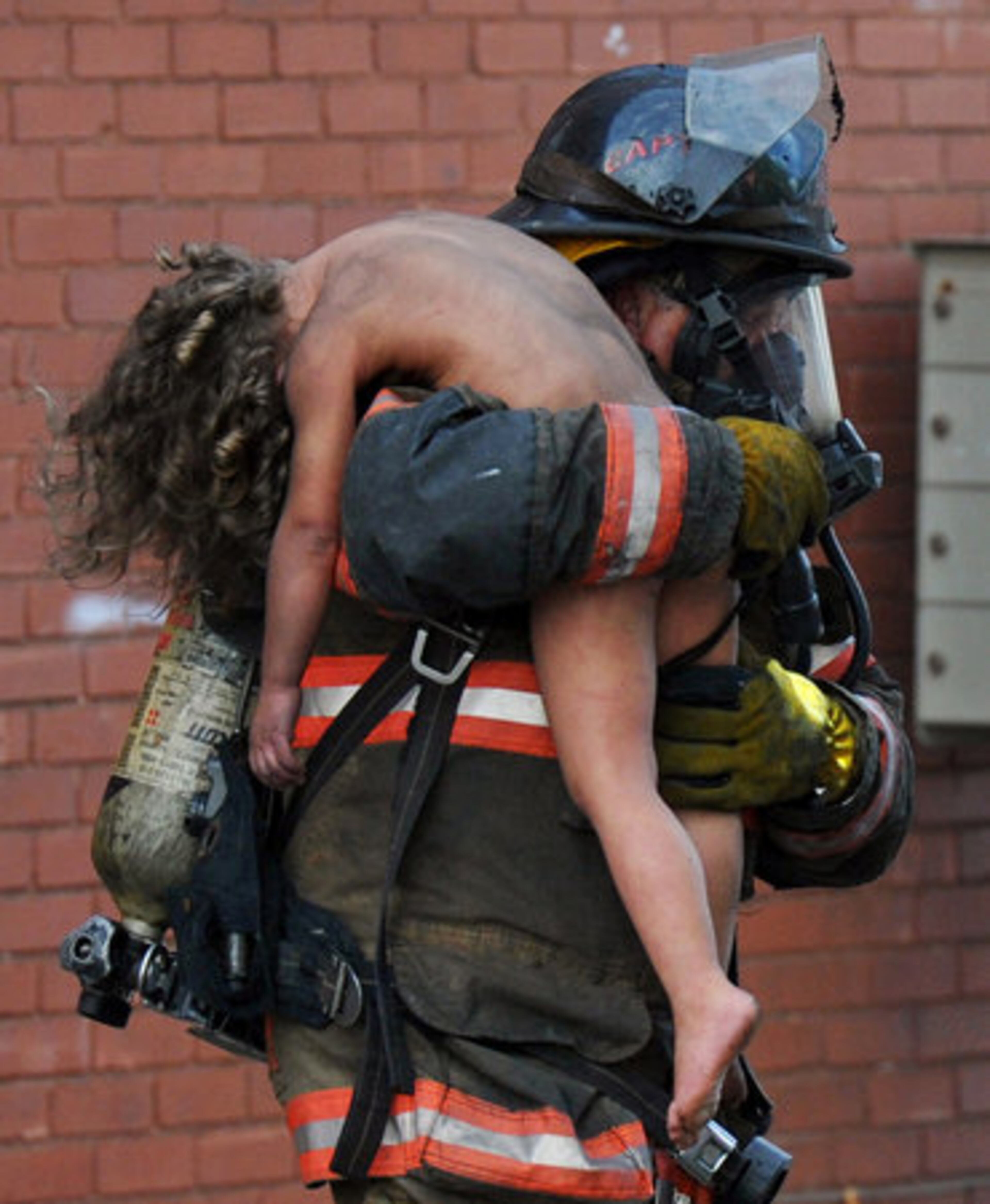 FILE -In this Sept. 7, 2011 file photo, Evansville fire Capt., Don Spindler carries a young girl out of a burning apartment in Evansville, Ind.