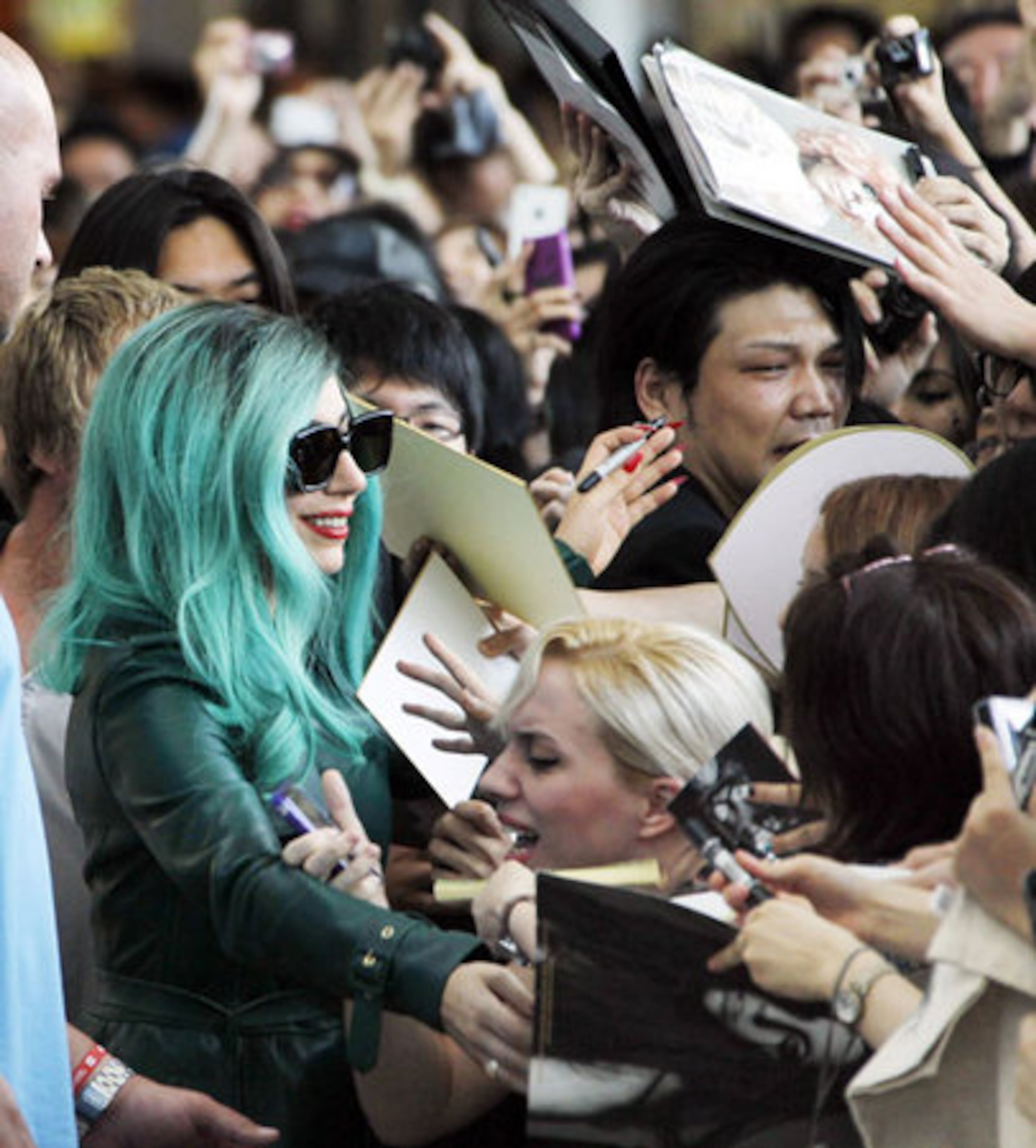 Fans hold signs, magazines, CDs and books out, hoping for an autograph while bodyguards keep the crowd at bay.