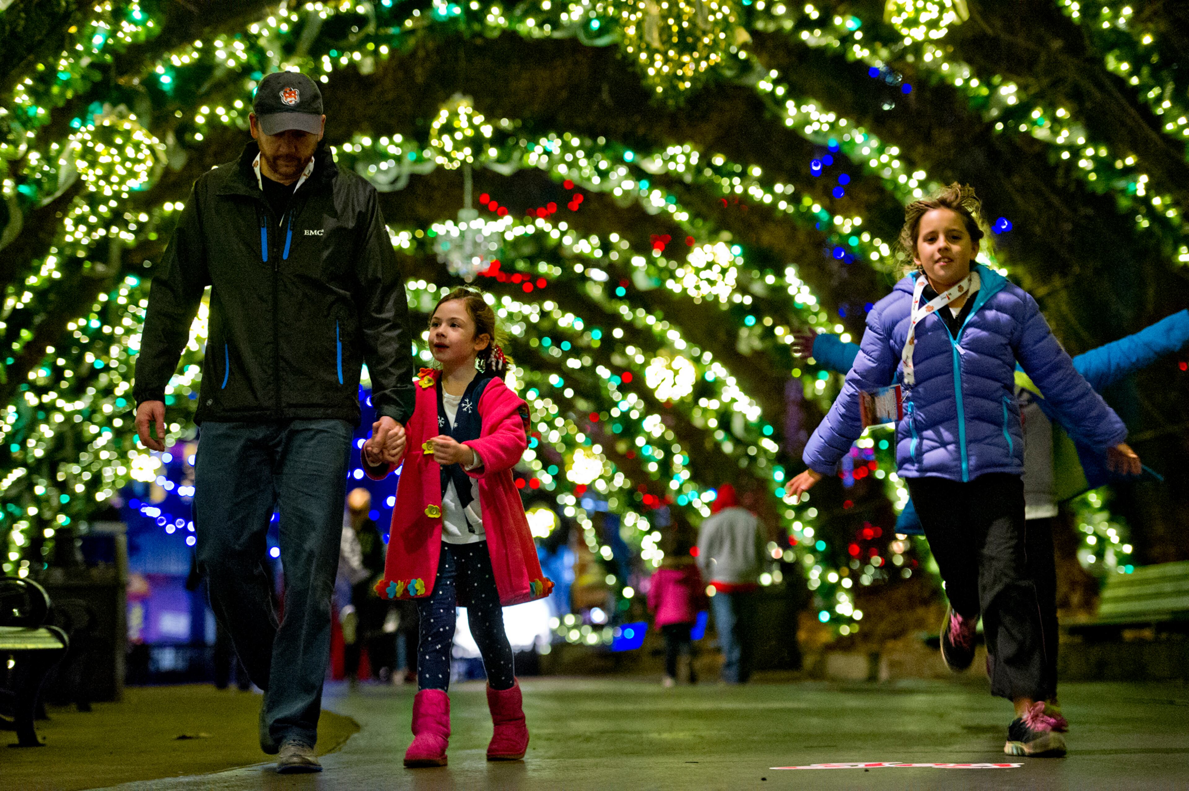Rob Wentz (left) holds hands with his daughter Harper as Hailey Ingram runs past inside Six Flags Over Georgia in Austell on Friday, November 21, 2014. The park has been decorated in 10 sections of holiday lights for the first time since 1990. Holiday in the Park runs through Jan.4, 2015. JONATHAN PHILLIPS / SPECIAL