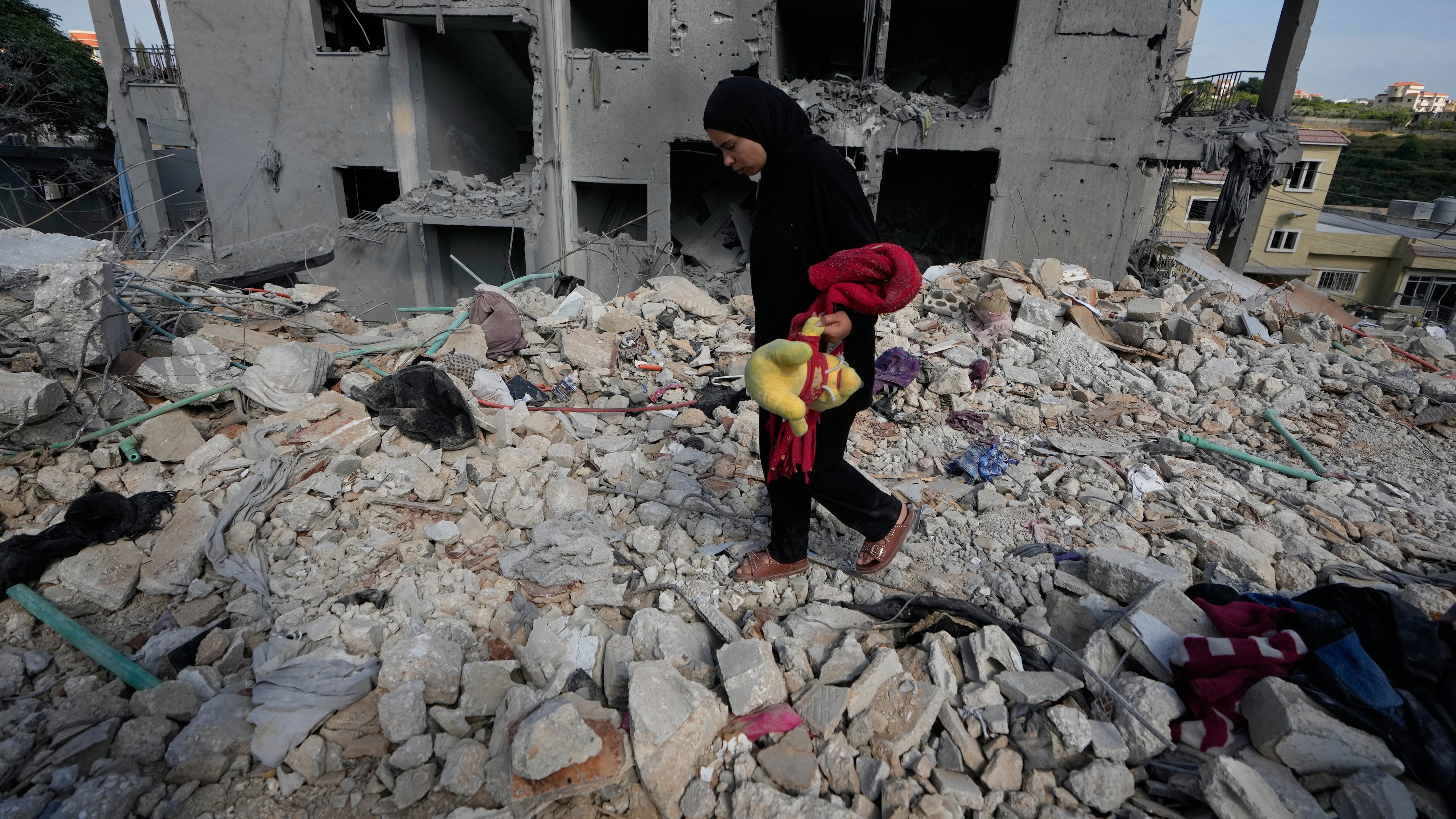 A resident carries belongings as she walks through the rubble of her home destroyed in an Israeli airstrike a day earlier in the southern village of Maarakeh, Lebanon, Wednesday, May 27, 2026. (AP Photo/Mohammed Zaatari)