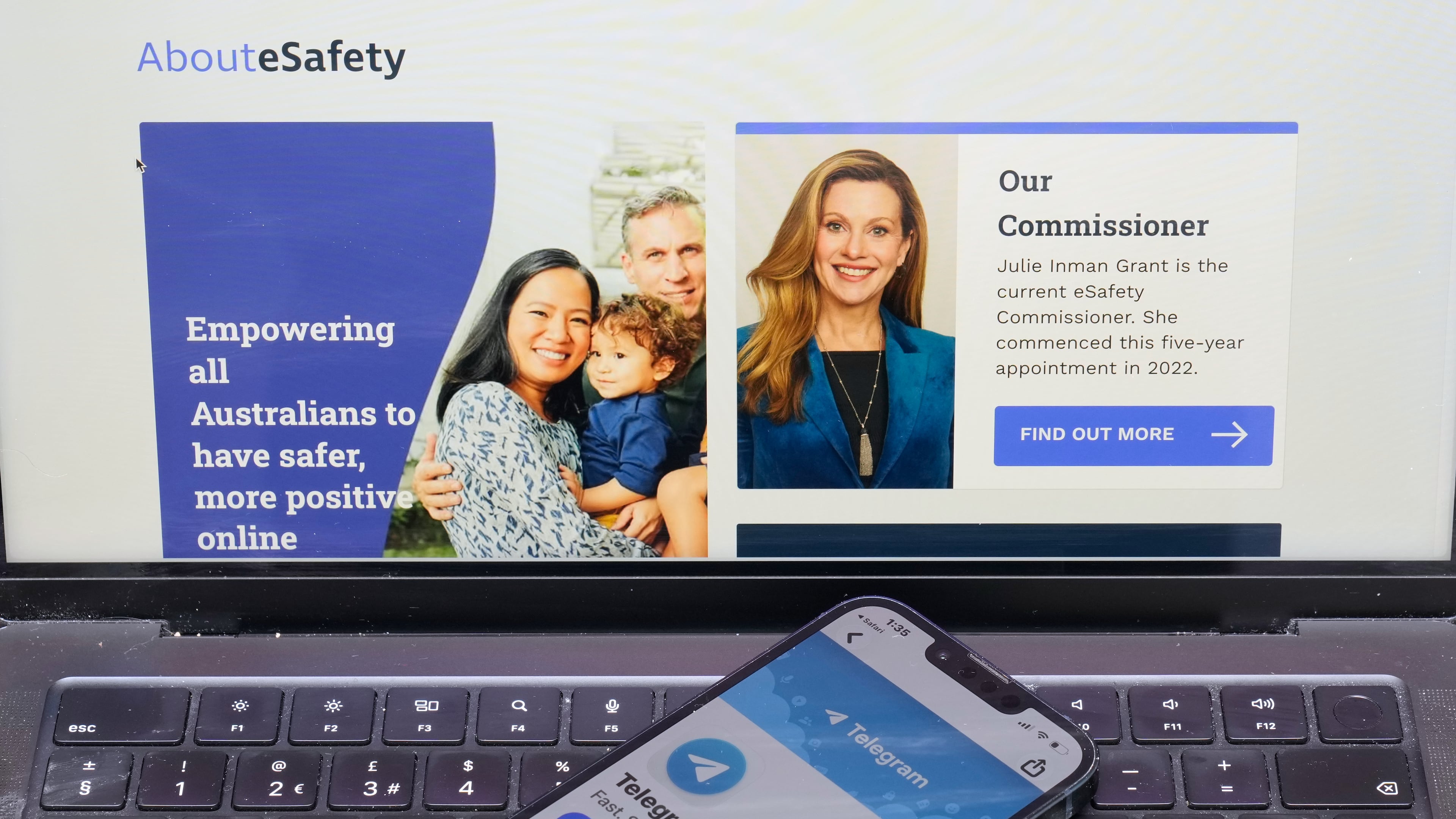 A phone rests on a computer showing the Australian eSafety web page in Sydney, Thursday, July 30, 2026. (AP Photo/Rick Rycroft)