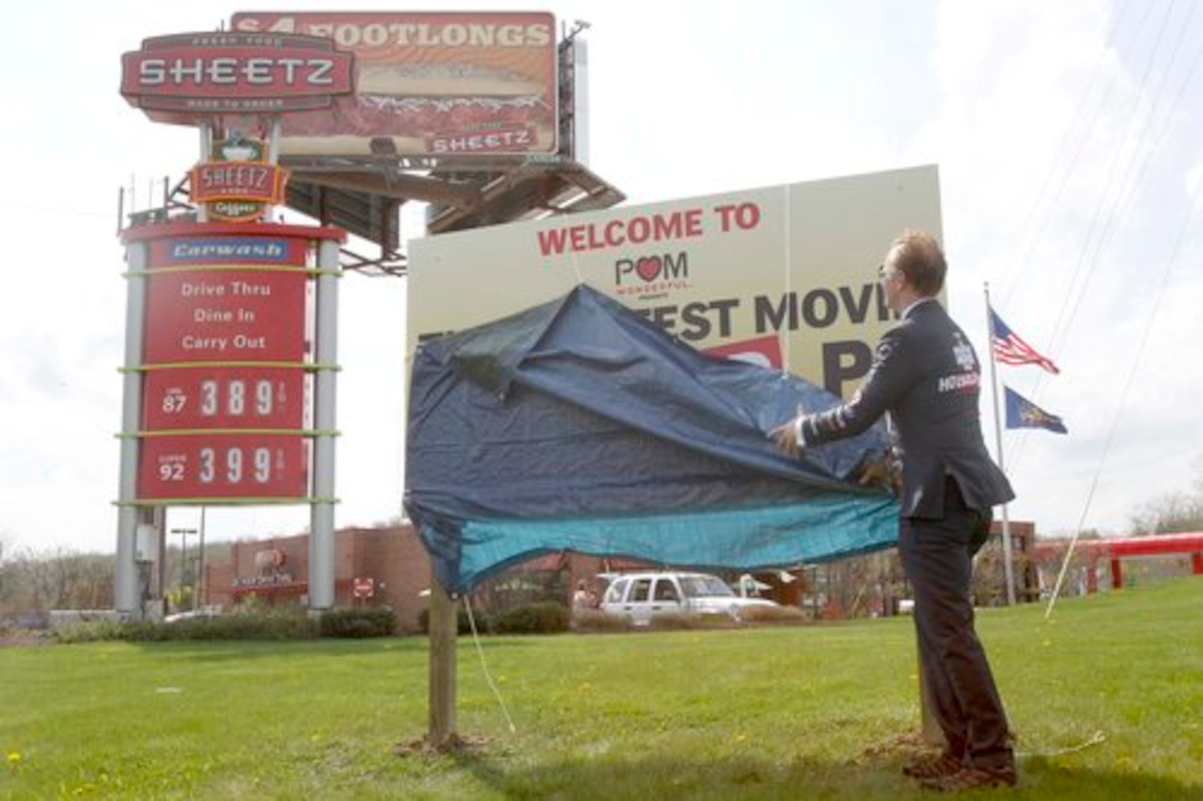 Documentary filmmaker Morgan Spurlock, wearing a suit with sponsors names stitched onto it, unveils signs changing the name of Altoona, Pa. to "POM Wonderful: The Greatest Movie Ever Sold.", Wednesday, April 27, 2011 in , Pa. Spurlock donated $25,000 to the city to rename itself so he could make a movie of the same name that lampoons the proliferation of advertising. The sign is in front of a Sheetz store, one of the major sponsors of the film.
