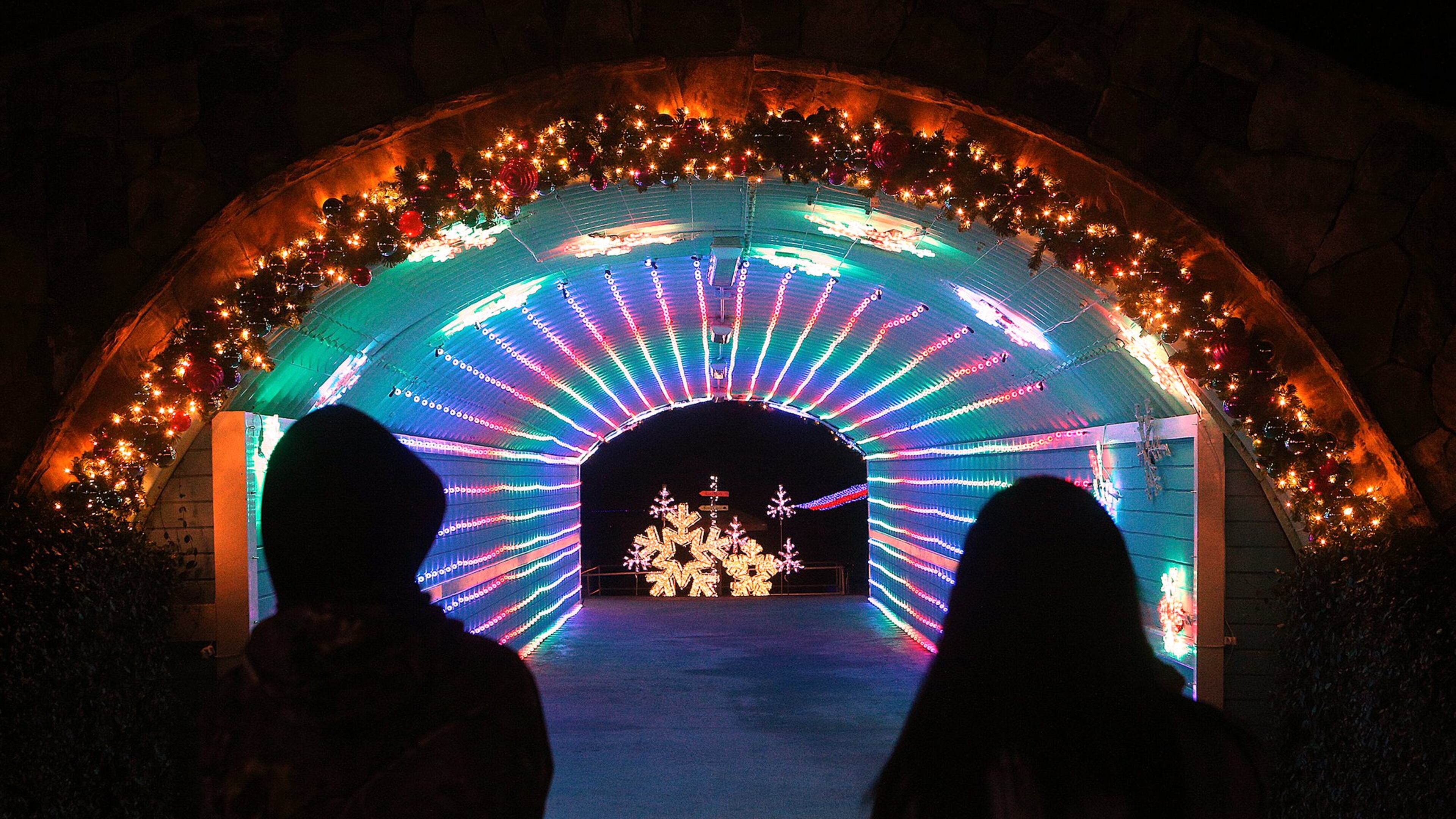 A pair of visitors take in the festive light display in a tunnel at Margaritaville in Lanier Islands in Buford. Curtis Compton/ccompton@ajc.com