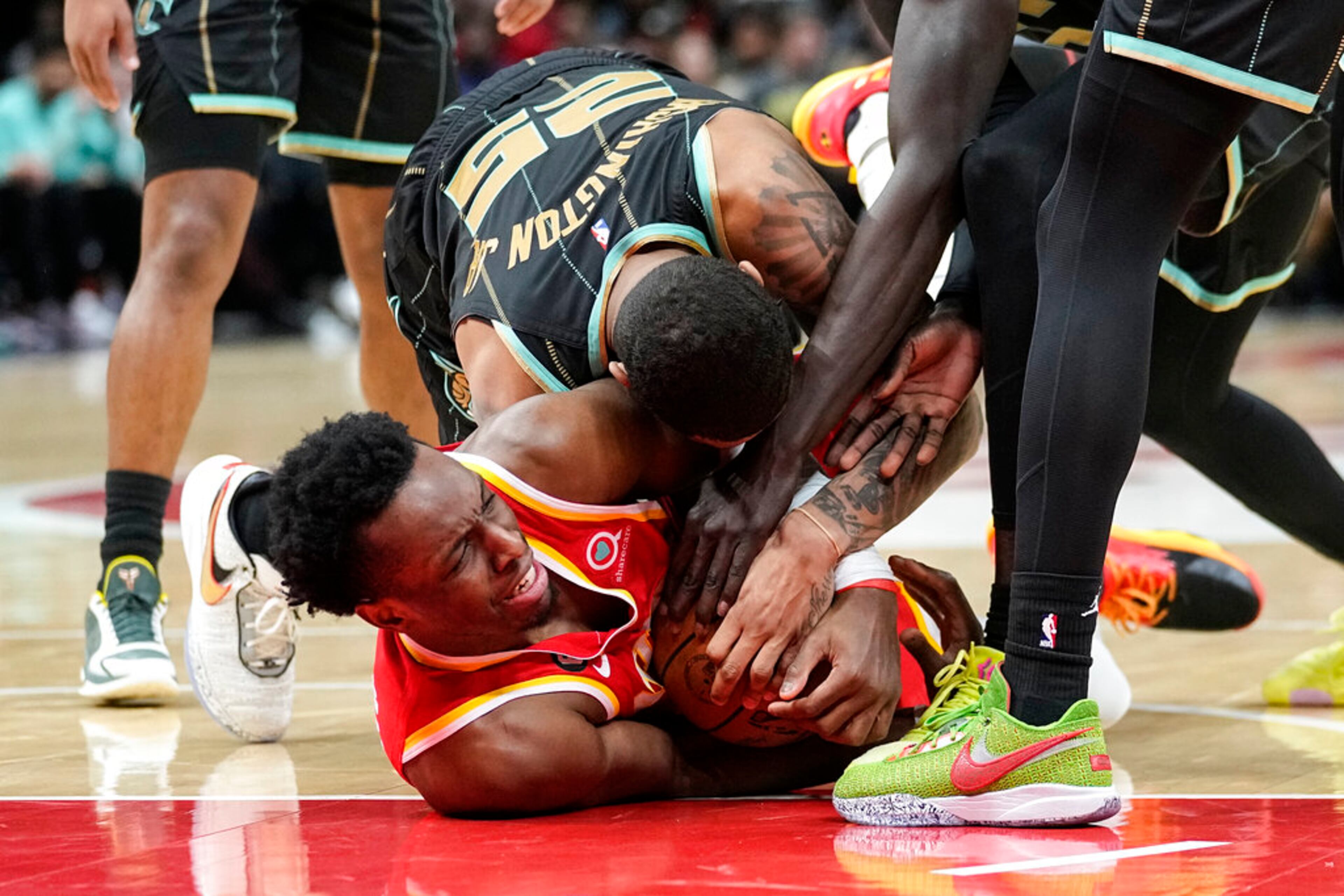 Atlanta Hawks forward Onyeka Okongwu, bottom, and Charlotte Hornets forward P.J. Washington (25) fight for possession of the ball during the first half of an NBA basketball game Saturday, Jan. 21, 2023, in Atlanta. (AP Photo/John Bazemore)