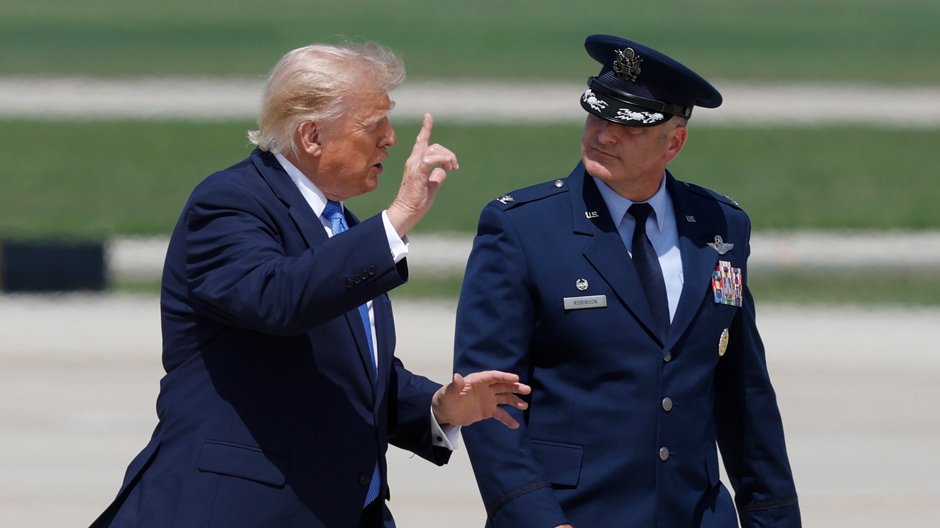 President Donald Trump, left, is escorted by Air Force Col. Christopher M. Robinson, commander of the 89th Airlift Wing, right, as he walk from Marine One to Air Force One, at Joint Base Andrews, Md., Tuesday, Aug. 4, 2026. (AP Photo/Luis M. Alvarez)