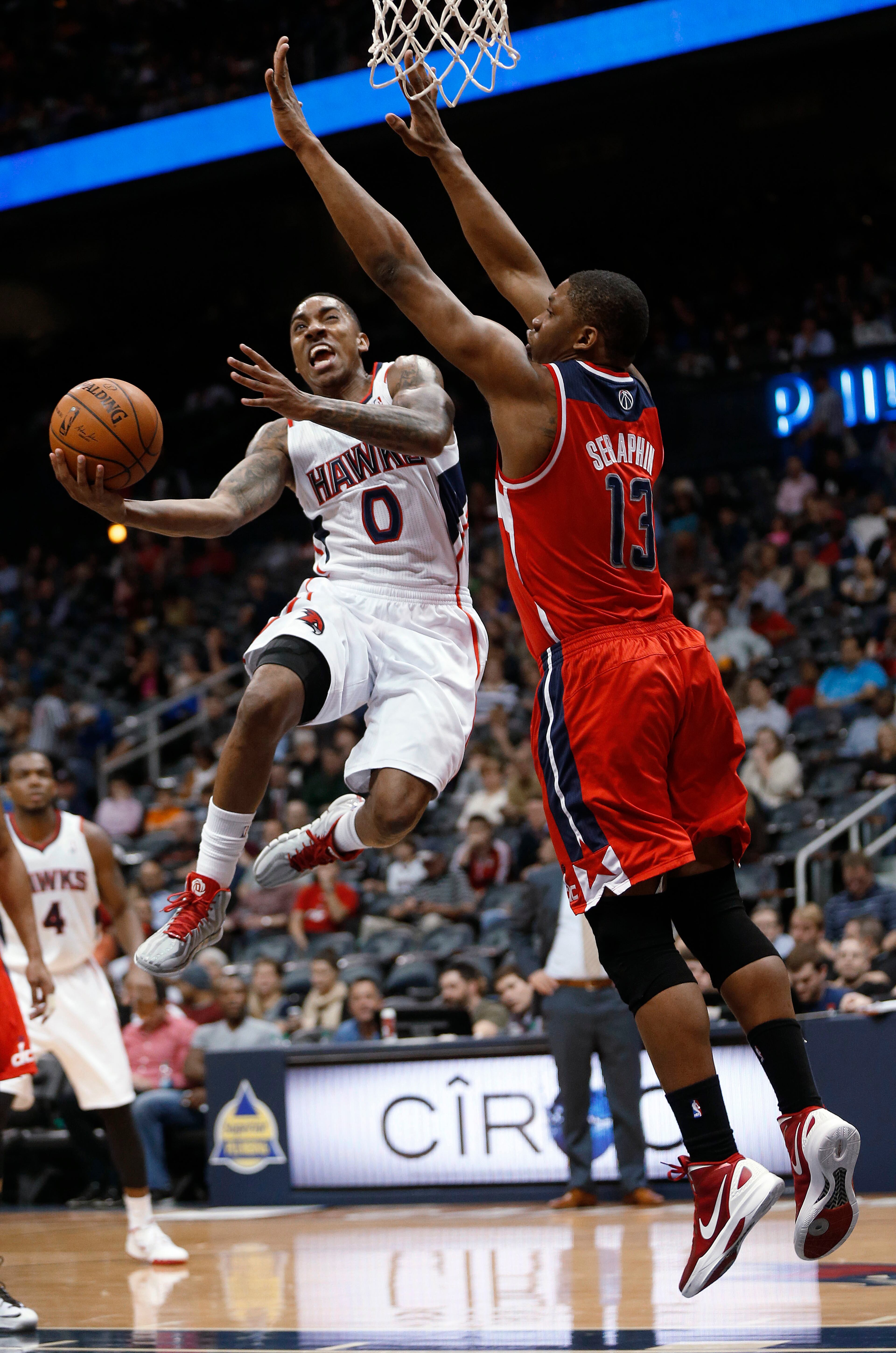 Atlanta Hawks guard Jeff Teague (0) goes up for a shot as Washington Wizards center Kevin Seraphin (13) defends during the first half of an NBA basketball basketball game Wednesday, Feb. 19, 2014, in Atlanta. Washington won 114-97. (AP Photo/John Bazemore)