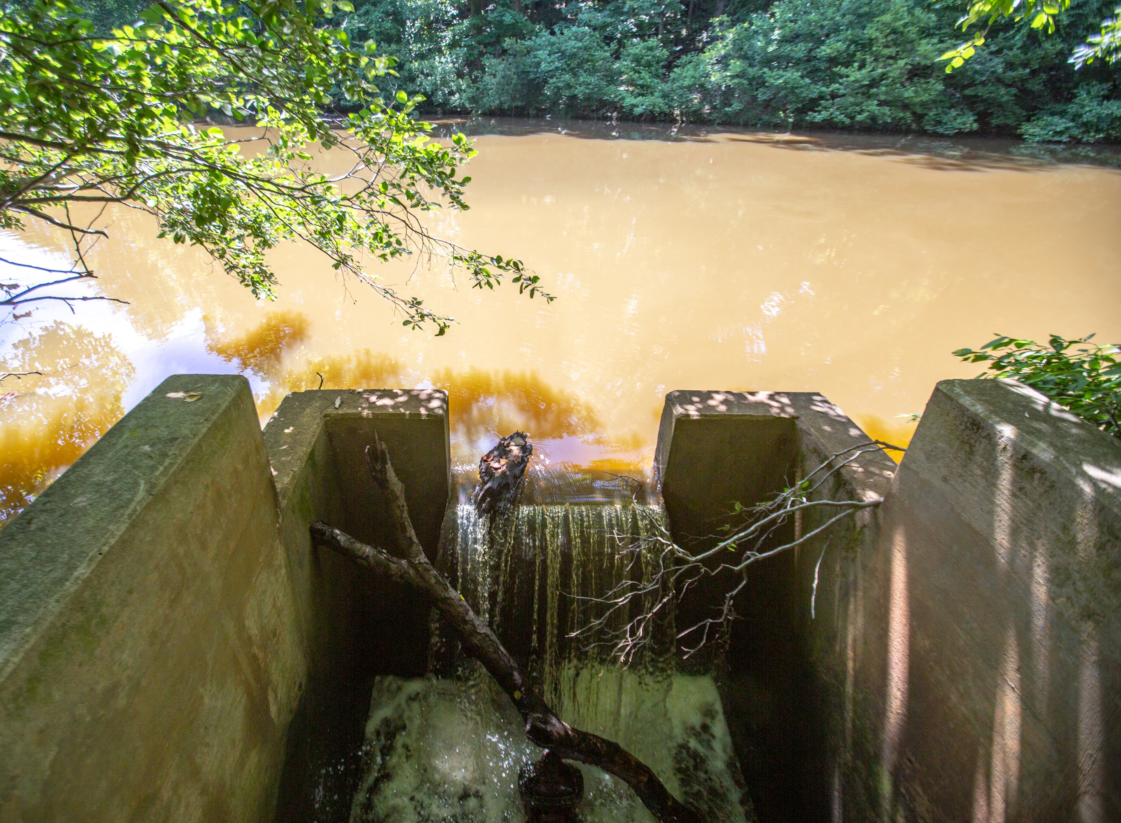 The detention pond, which collects runoff beyond the subdivisions boundaries, exits the pond here, and it's unclear who is to maintain the infrastructure. The water rushes from here and begins to cut through residents' backyards (Jenni Girtman for The Atlanta Journal-Constitution)