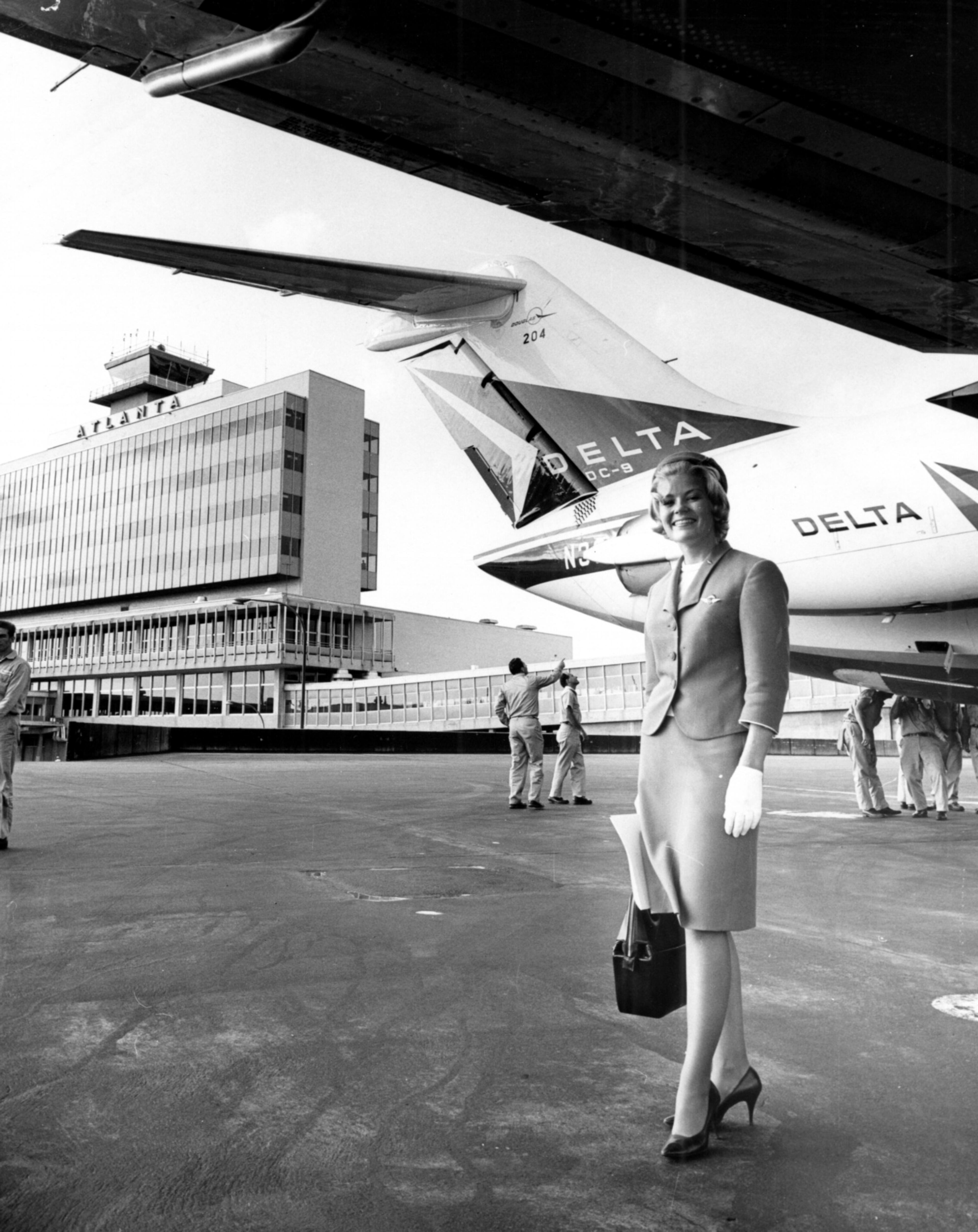 Oct. 9, 1965 - Atlanta, Ga.: Delta Air Lines stewardess Carol Koberlein poses in front of the new Delta DC-9. In the distance is the then-recently built Atlanta Airport (opened 1961), which was considered among the country's most modern airports of its time. It was demolished when Hartsfield-Jackson was opened in 1980.