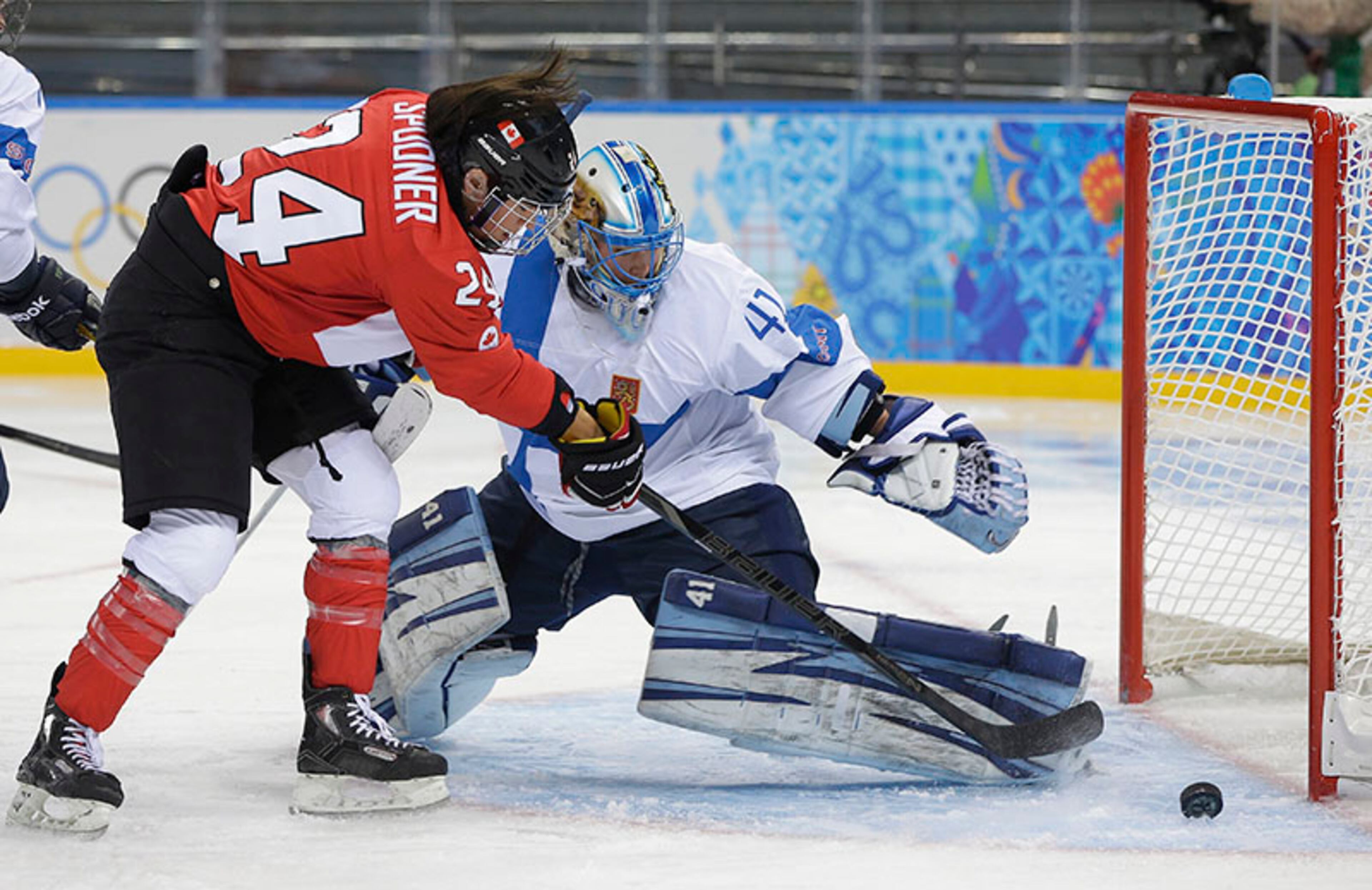 Natalie Spooner of Canada makes an unsuccessful attempt at a goal as Goalkeeper Noora Raty of Finland watches the puck slide past the net during the second period of the 2014 Winter Olympics women's ice hockey game at Shayba Arena, Monday, Feb. 10, 2014, in Sochi, Russia.