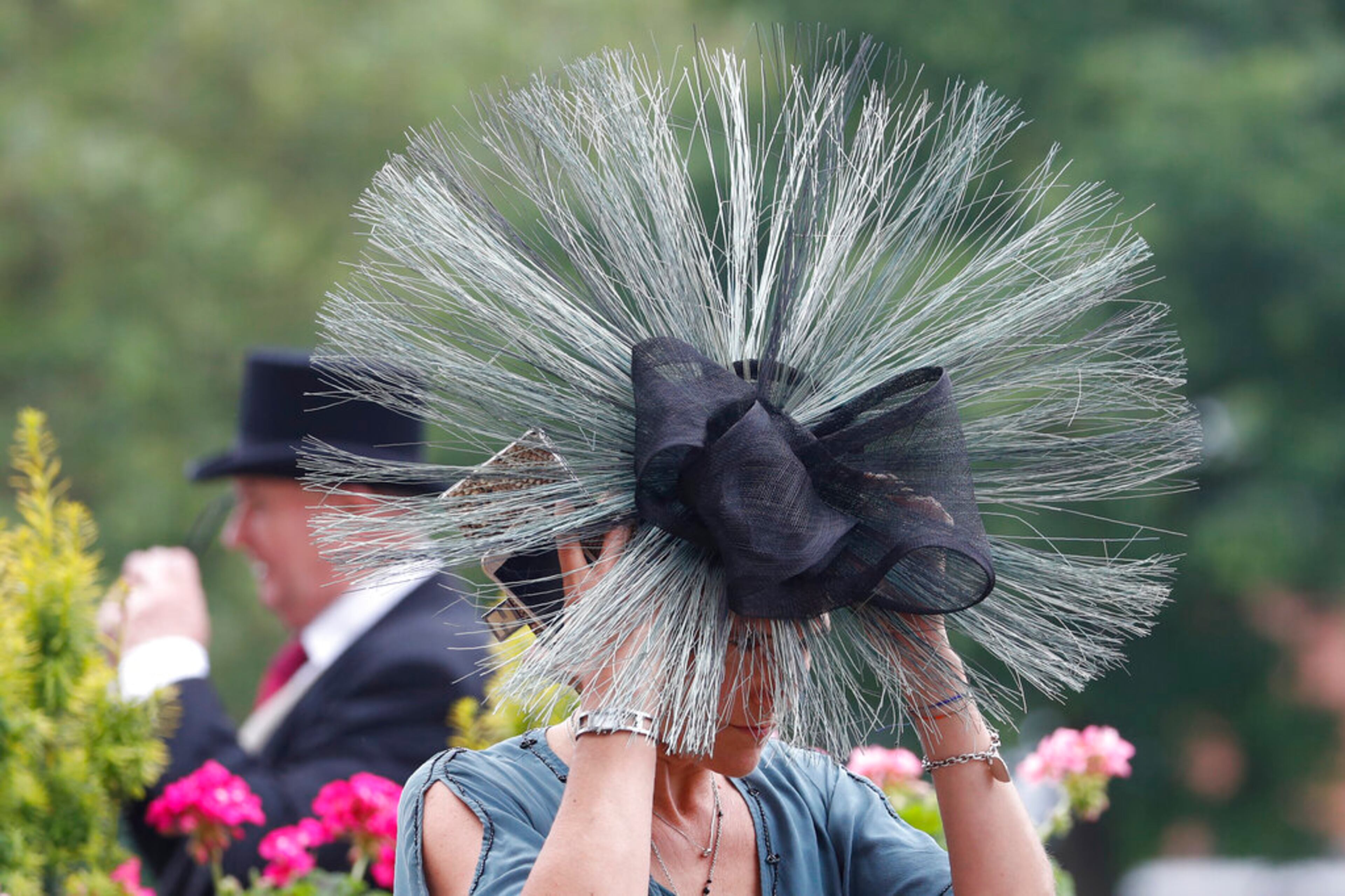 A racegoer adjusts her hat as she arrives on the second day of the annual Royal Ascot horse race meeting in Ascot, England, Wednesday, June 19, 2019. (AP Photo/Alastair Grant)