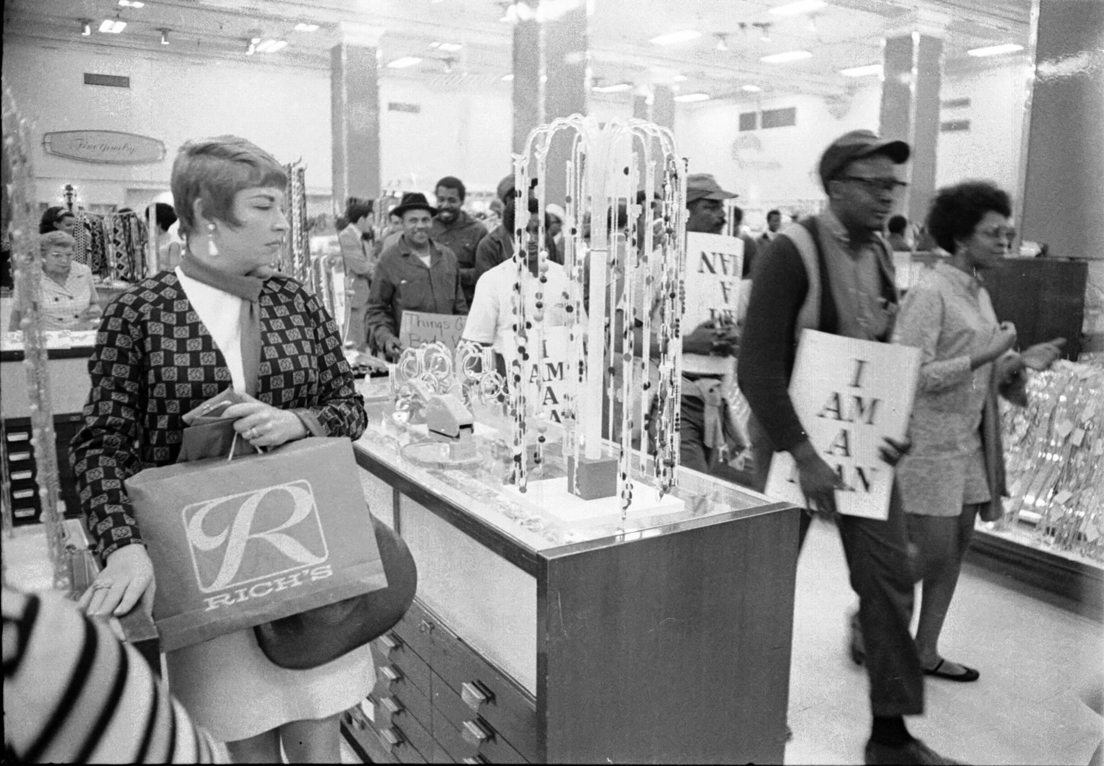 April 1970 -- Atlanta city workers on a strike march make their way through the downtown Rich's store as customers look on.