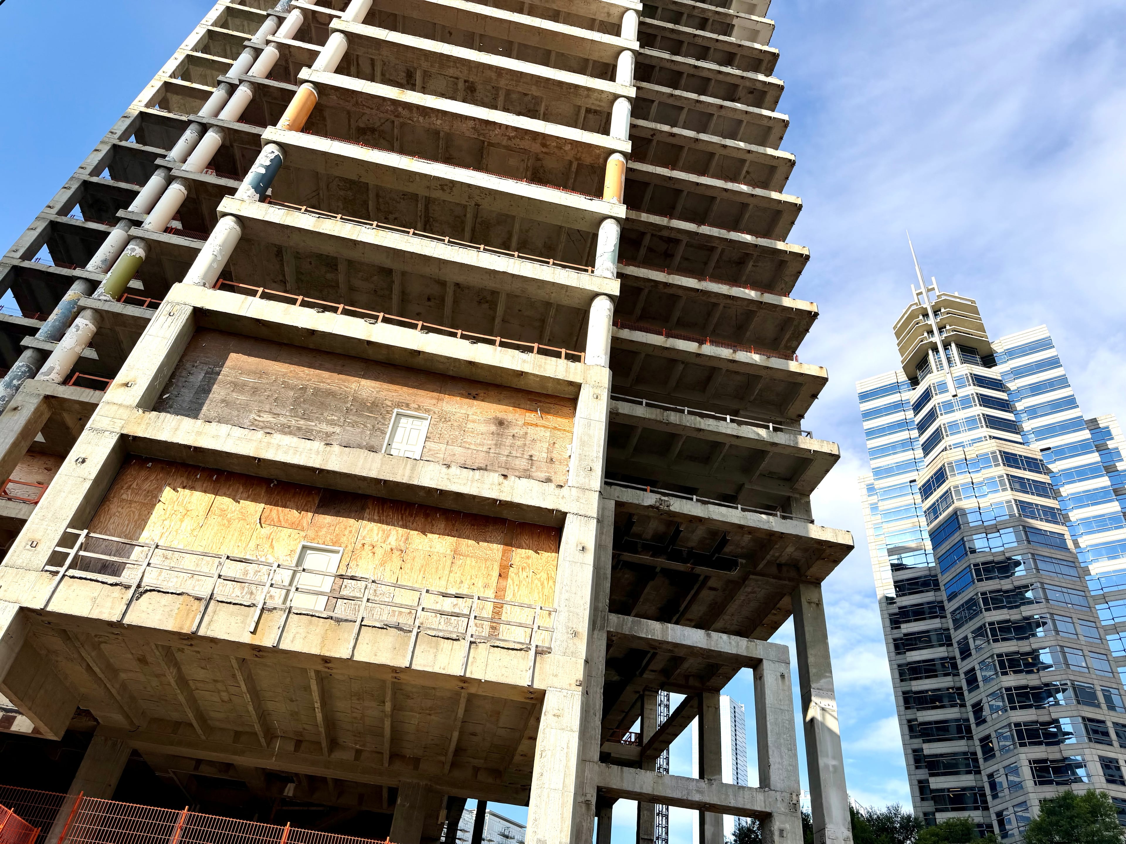 The Campanile building, left, at the corner of Peachtree and 14th streets as seen on Thursday, Sept. 10, 2026. Exposed floors of the vacant tower, which developer John Dewberry has dubbed The Midtowne, contrast with occupied office towers in Midtown such as Proscenium, right. (J. Scott Trubey/AJC)