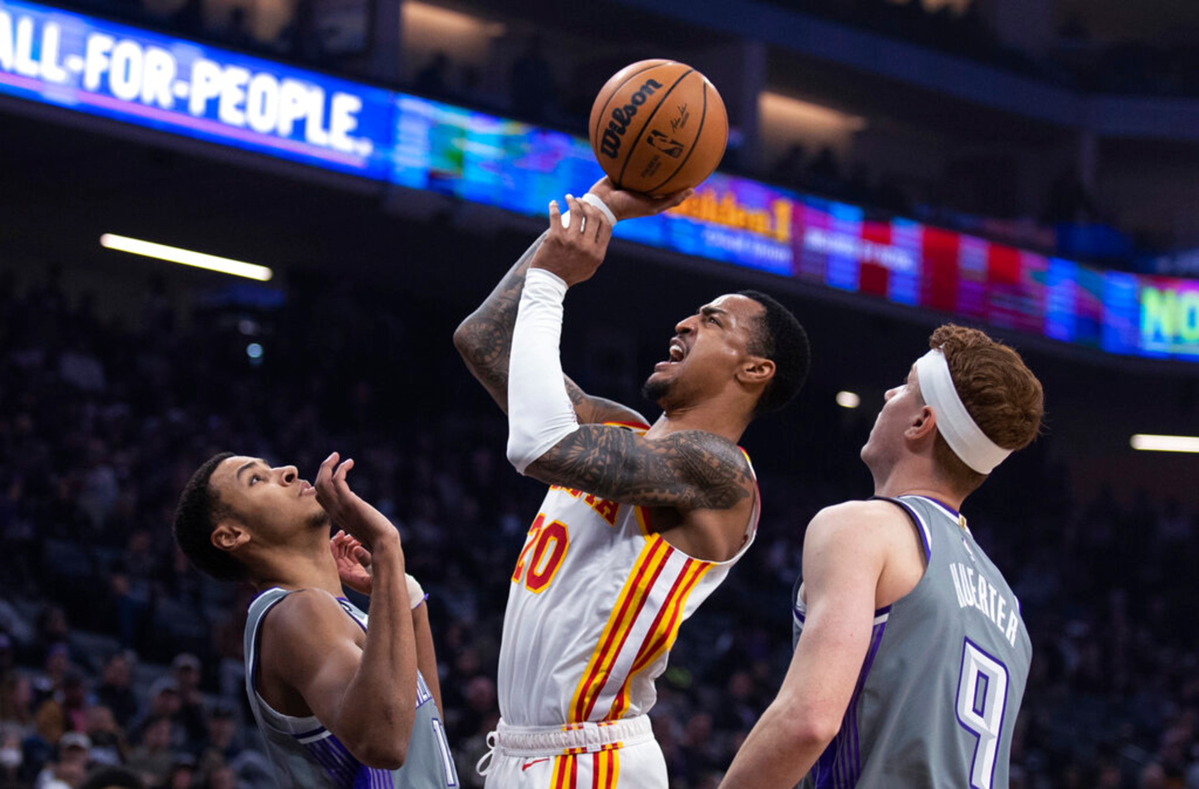 Atlanta Hawks forward John Collins (20) shoots from between Sacramento Kings forward Keegan Murray (13) and guard Kevin Huerter (9) during the first quarter of an NBA basketball game in Sacramento, Calif., Wednesday, Jan. 4, 2023. (AP Photo/José Luis Villegas)