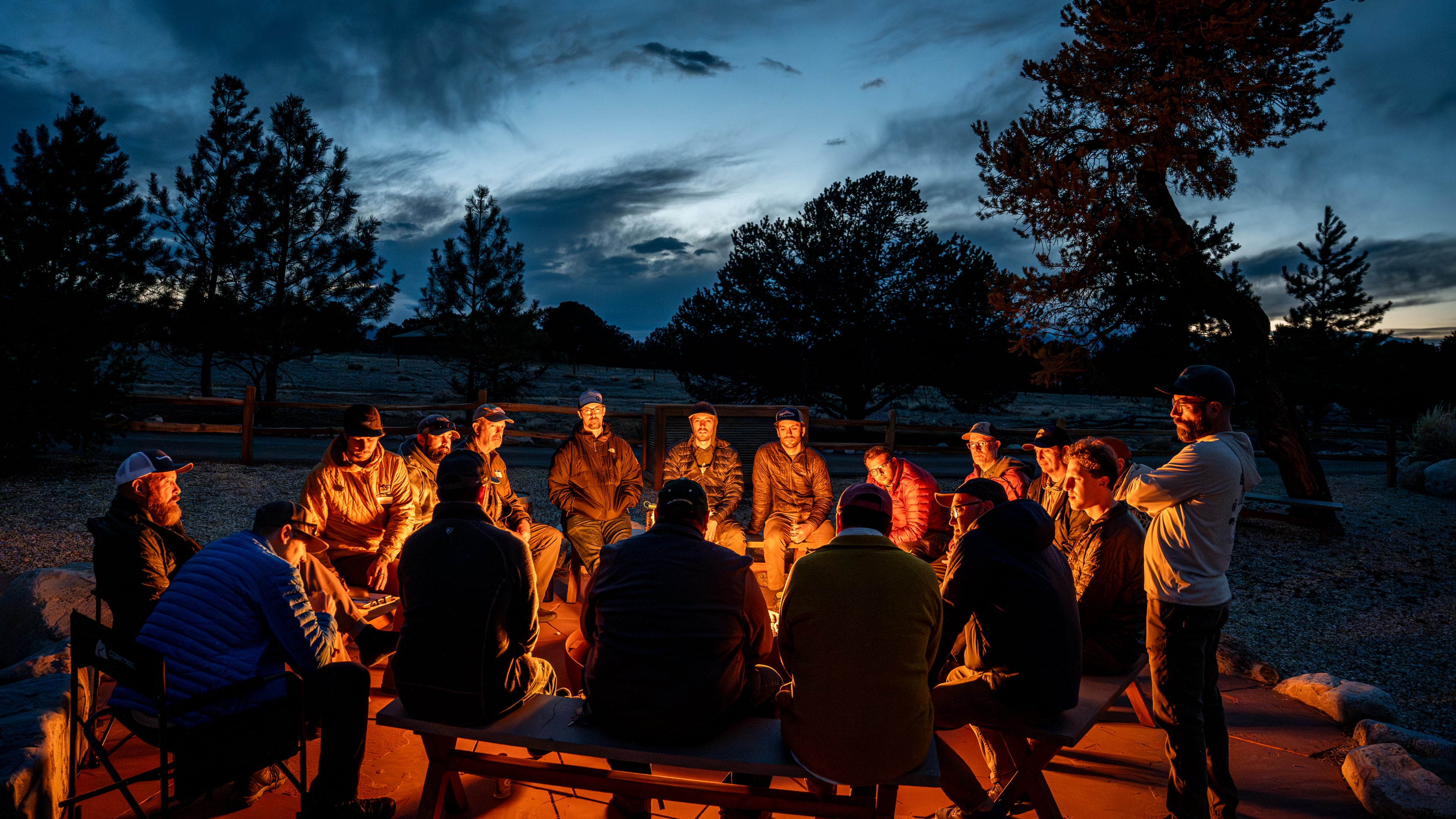 Men gather around a campfire during a Fishing the Good Fight retreat, connecting through the outdoors and conversations about mental health. (Courtesy of Fishing the Good Fight)