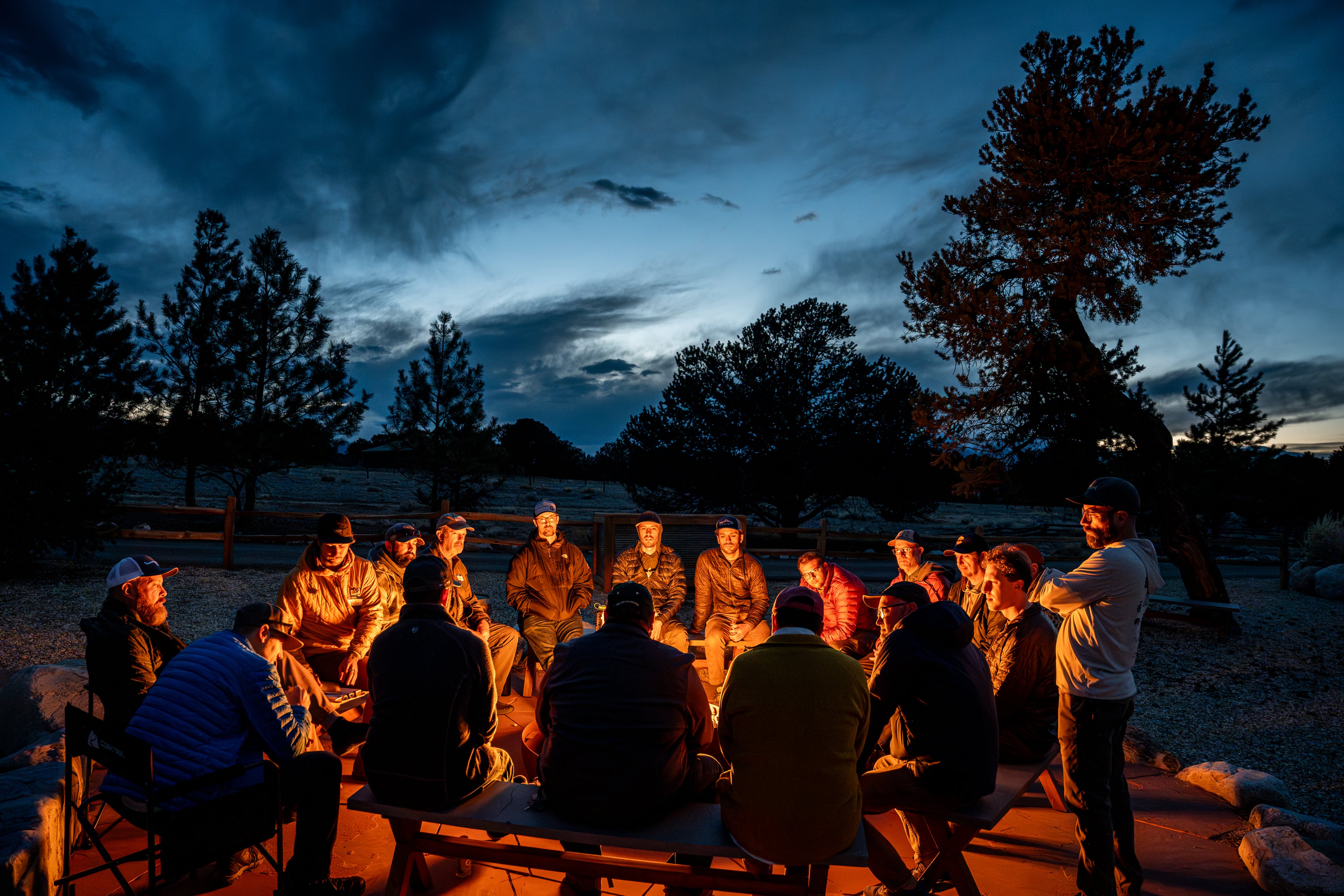 Men gather around a campfire during a Fishing the Good Fight retreat, connecting through the outdoors and conversations about mental health. (Courtesy of Fishing the Good Fight)