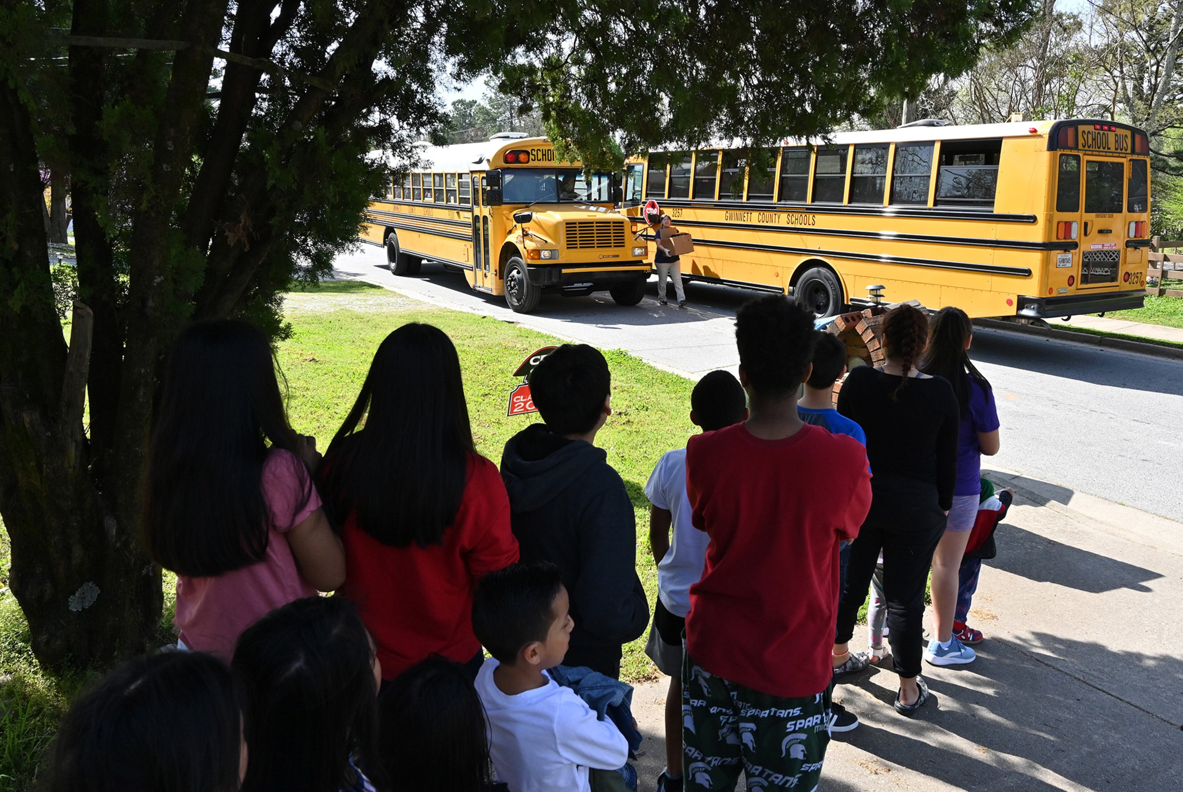 March 20, 2020 Norcross - Children wait for a Gwinnett County school bus arriving to receive a free meal at their school bus stop on Friday, March 20, 2020. Gwinnett County Schools offers meal pickup at 68 sites and bus stops near the schools from 11 a.m. to 1 p.m. for children 18 and under. (Hyosub Shin / Hyosub.Shin@ajc.com)
