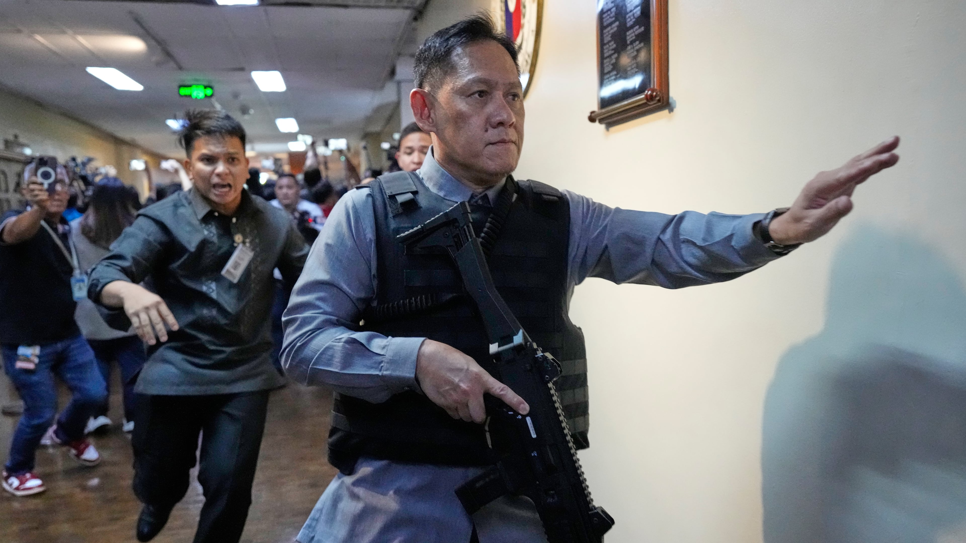 Senate security run after gunfire was heard along a hallway at the Philippine Senate in Pasay, Philippines, Wednesday, May 13, 2026. (AP Photo/Aaron Favila)