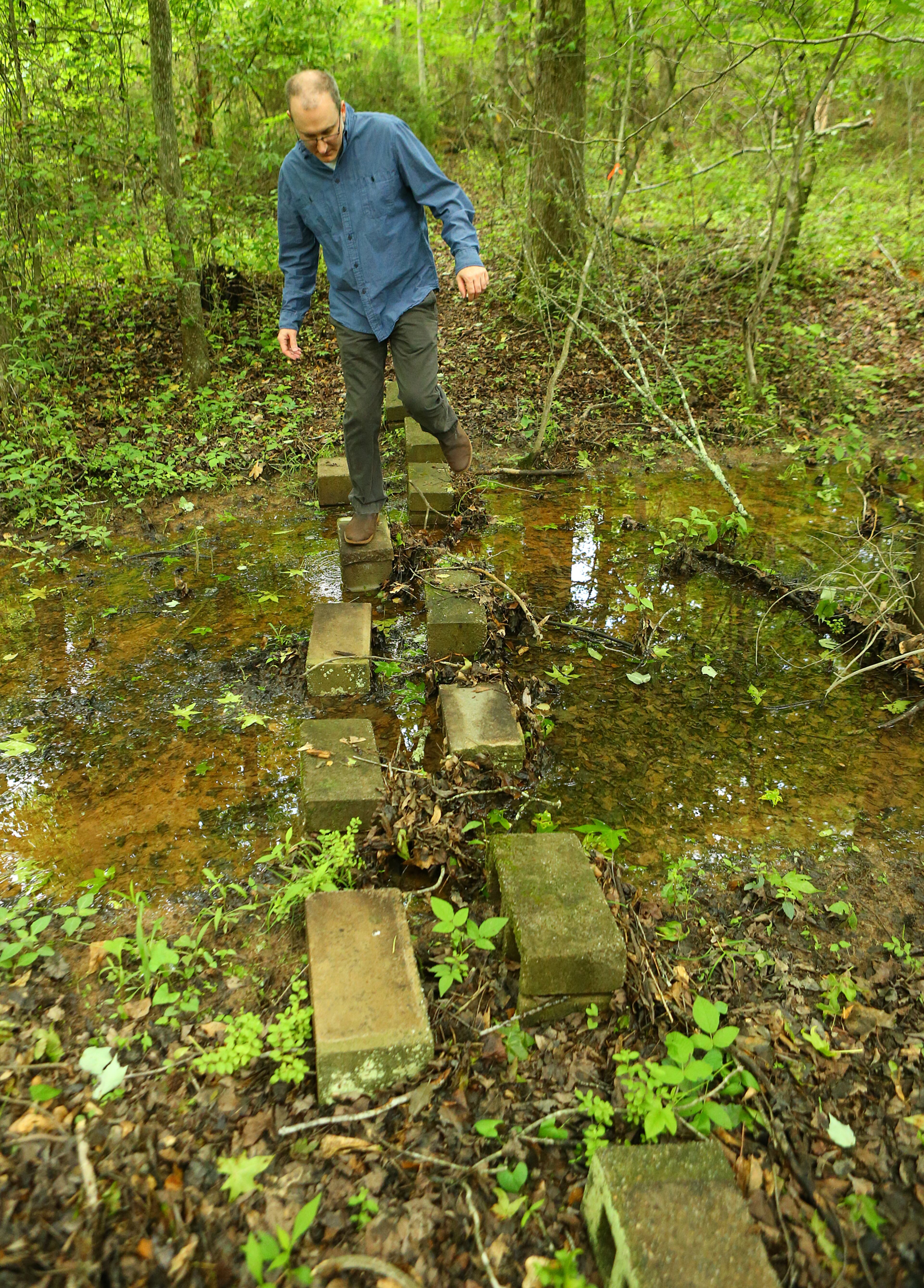 Paul Cooper crosses over a spring fed creek on the 50 acre farm of his grandmother Miss Besse Cooper on Monday, May 19, 2014, in Monroe. Cooper was the oldest person in the world until she died at the age of 116 years and 100 days in 2012. CURTIS COMPTON / CCOMPTON@AJC.COM