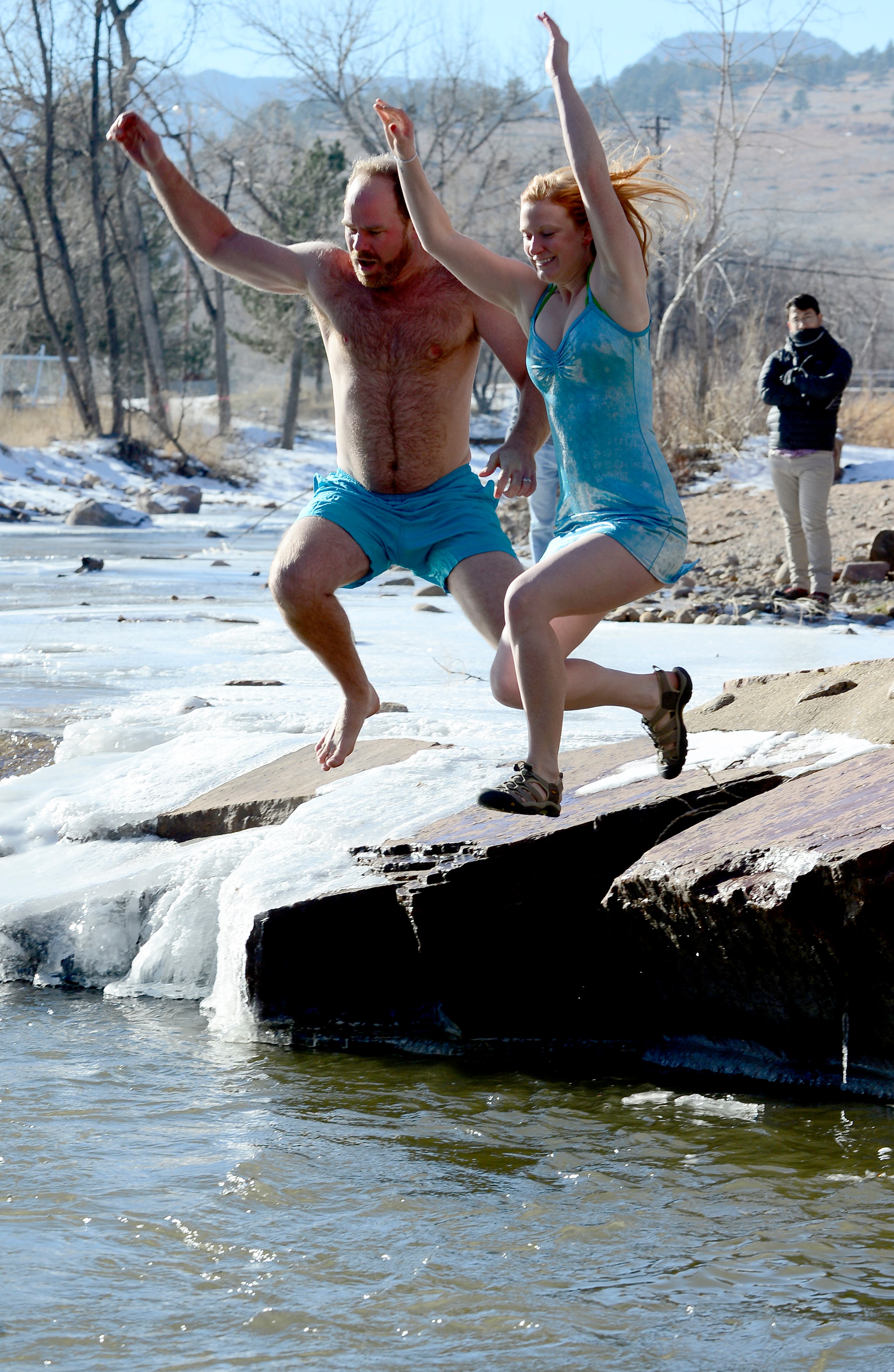 Plunge organizer, Jason Stillman, left, and his wife Sarah, take the plunge on Friday, Jan. 1, 2016, during the annual Lyons Polar Plunge held at the "Black Bear Hole" of the St. Vrain River in Lyons, Colo. (Cliff Grassmick /Daily Camera via AP)
