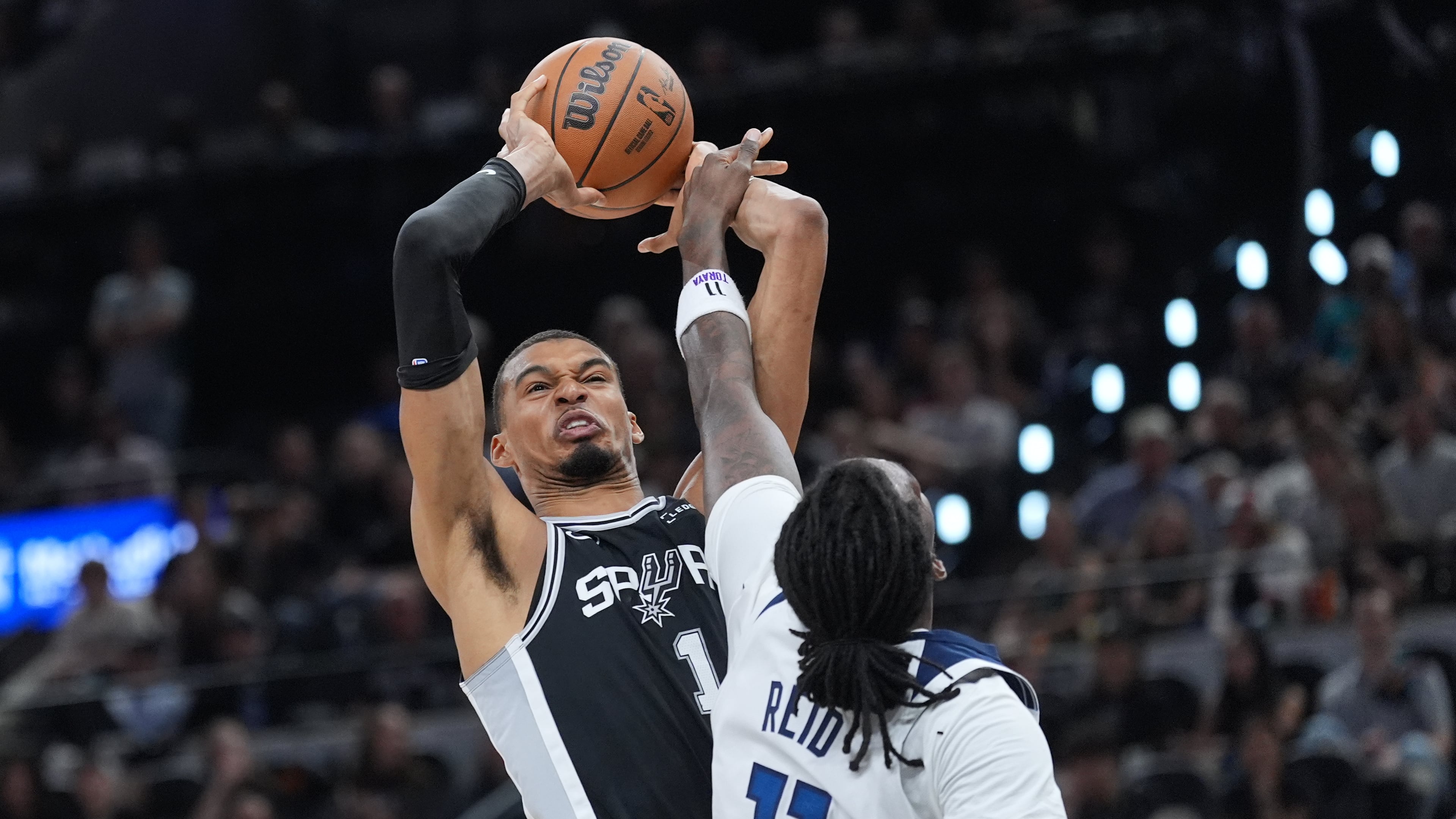 San Antonio Spurs forward Victor Wembanyama (1) grabs a rebound over Minnesota Timberwolves center Naz Reid (11) during the first half of Game 5 of an NBA basketball second-round playoffs series in Minneapolis, Tuesday, May 12, 2026. (AP Photo/Eric Gay)