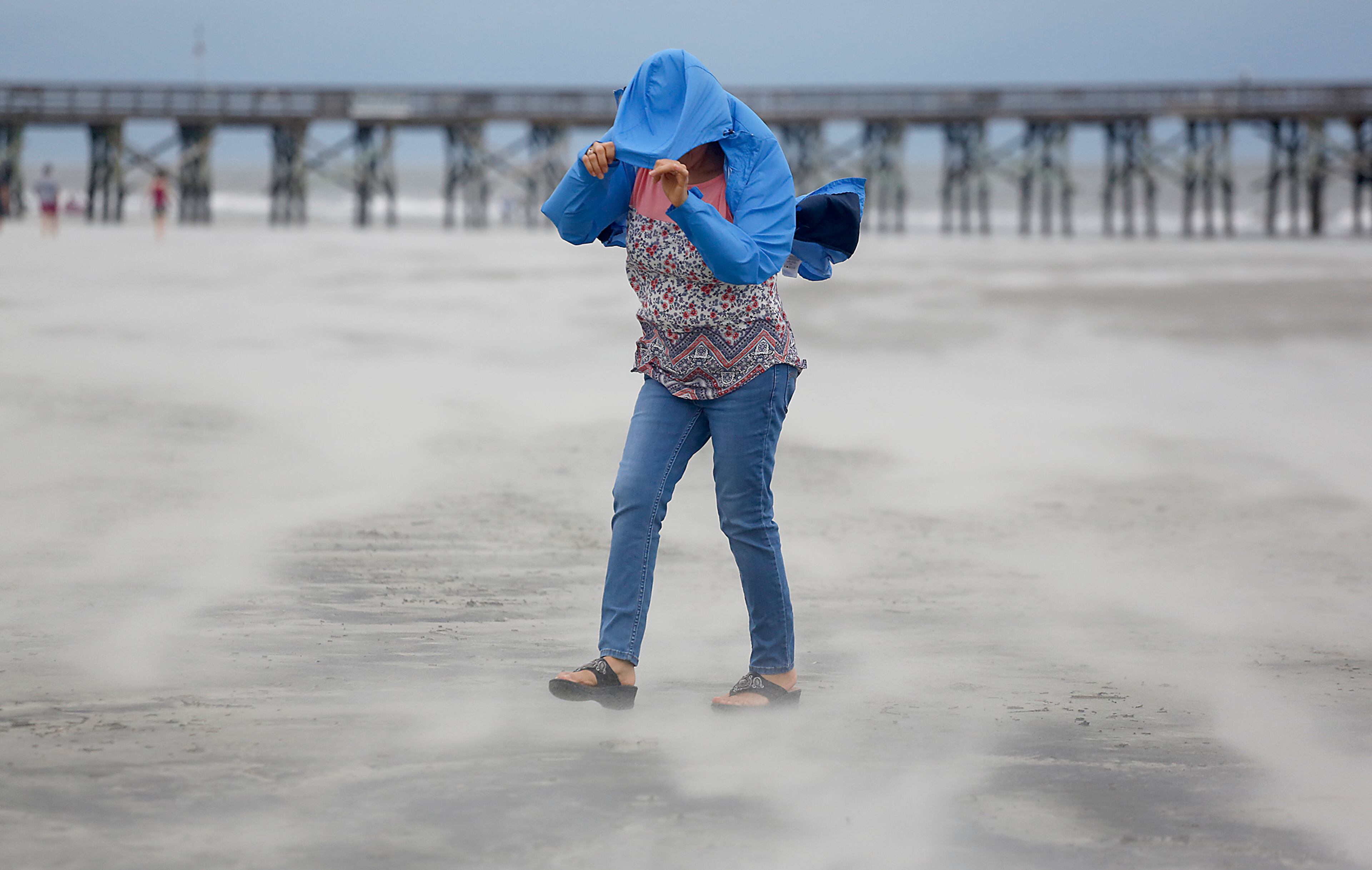 Marian Rivera covers her face from the strong wind and blowing sand as Tropical Storm Florence approaches the Isle of Palms, S.C., Friday, Sept. 14, 2018. (AP Photo/Mic Smith)