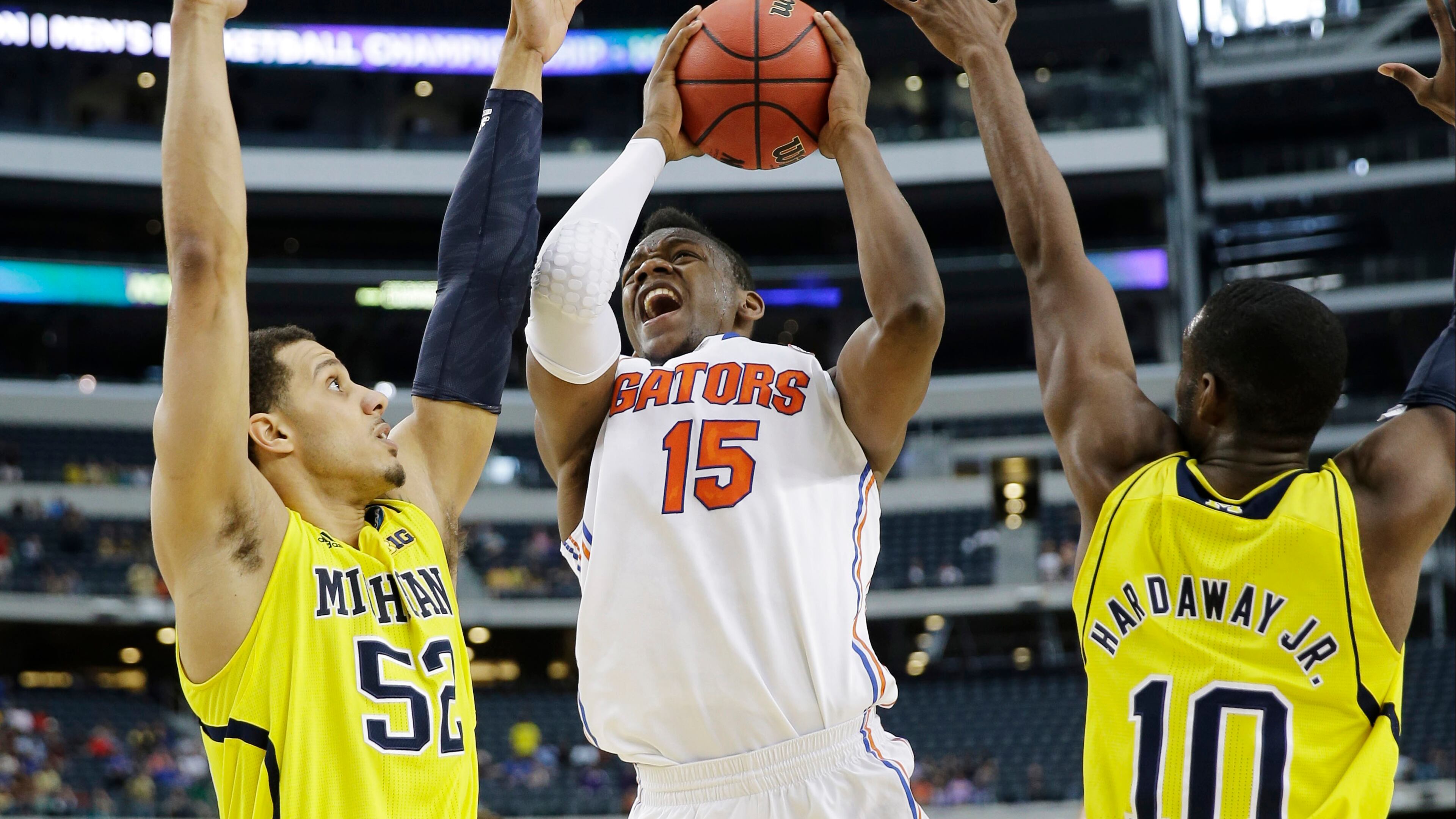 Florida forward Will Yeguete (15) shoots between Michigan's Jordan Morgan (52) and Michigan's Tim Hardaway Jr. (10)during the first half of a regional final game in the NCAA college basketball tournament, Sunday, March 31, 2013, in Arlington, Texas. (AP Photo/David J. Phillip)