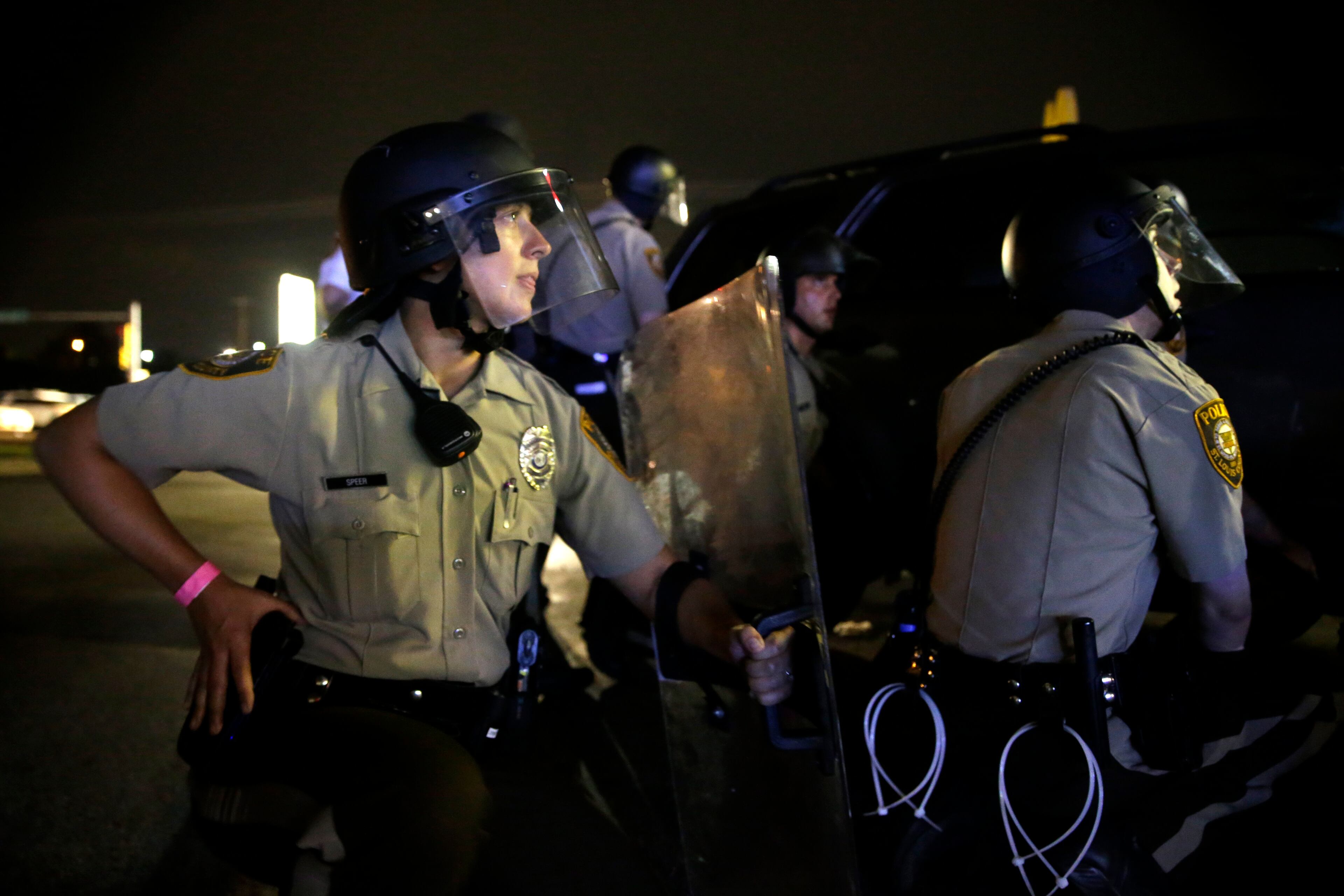 Police take cover after gunfire near a protest in Ferguson, Mo., Sunday, Aug. 9, 2015. The one-year anniversary of Michael Brown's death in Ferguson began with a march in his honor and ended with a protest that was interrupted by gunfire. (AP Photo/Jeff Roberson)