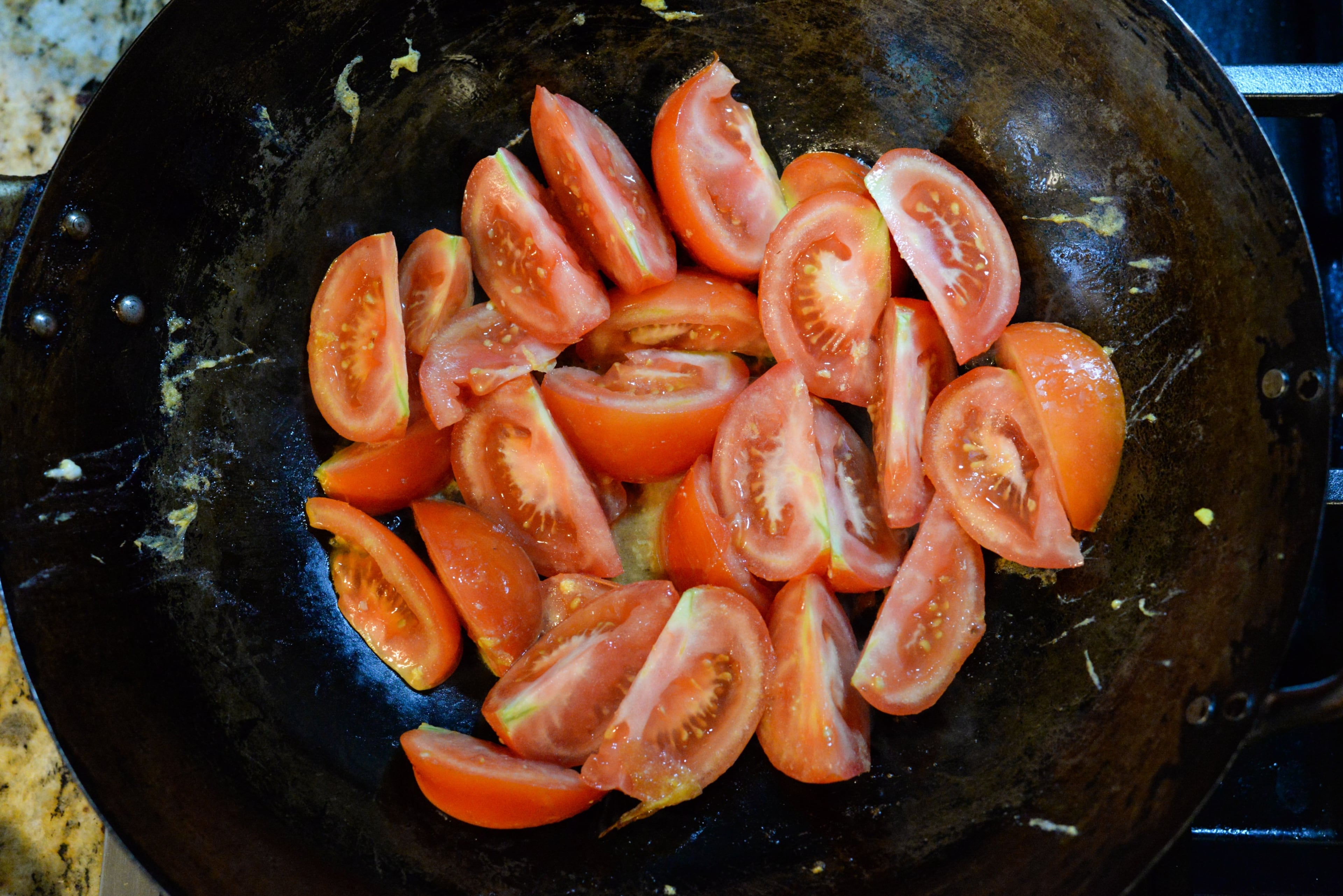 Return the wok to high heat. When the wok is smoking, add the remaining 2 tablespoons oil. When the oil is shimmering, add the tomatoes and cook until they begin to release their juices, about 3 to 4 minutes. Cook them an extra 2 minutes if you prefer softer tomatoes. (Candy Hom for the AJC)