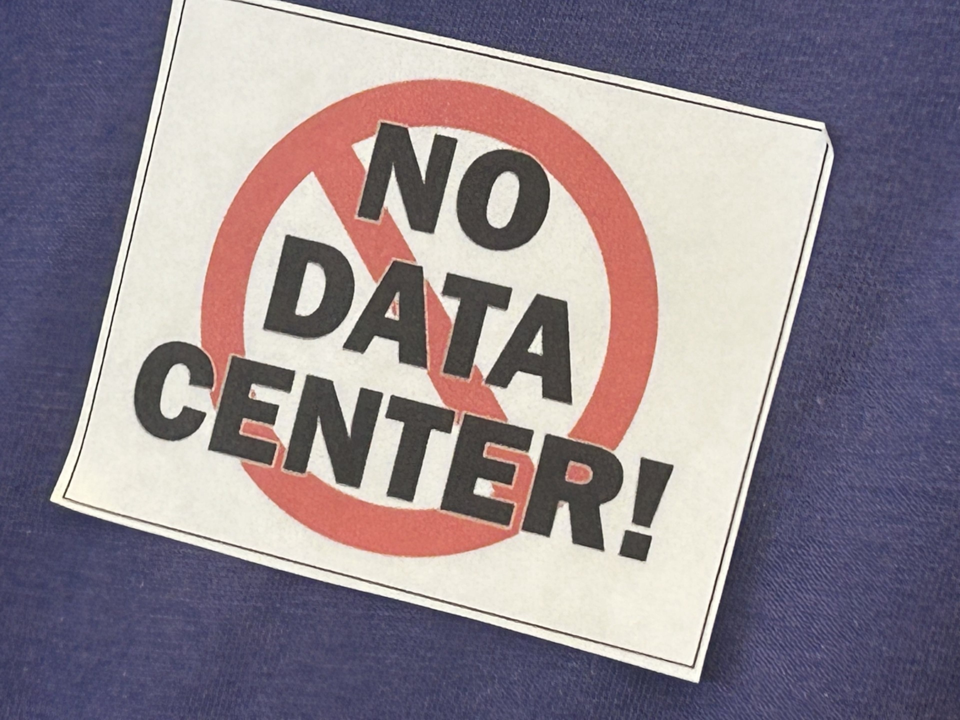 Many OpenAI data center open house attendees sported stickers opposing the proposed project. (Adam Van Brimmer/AJC)
