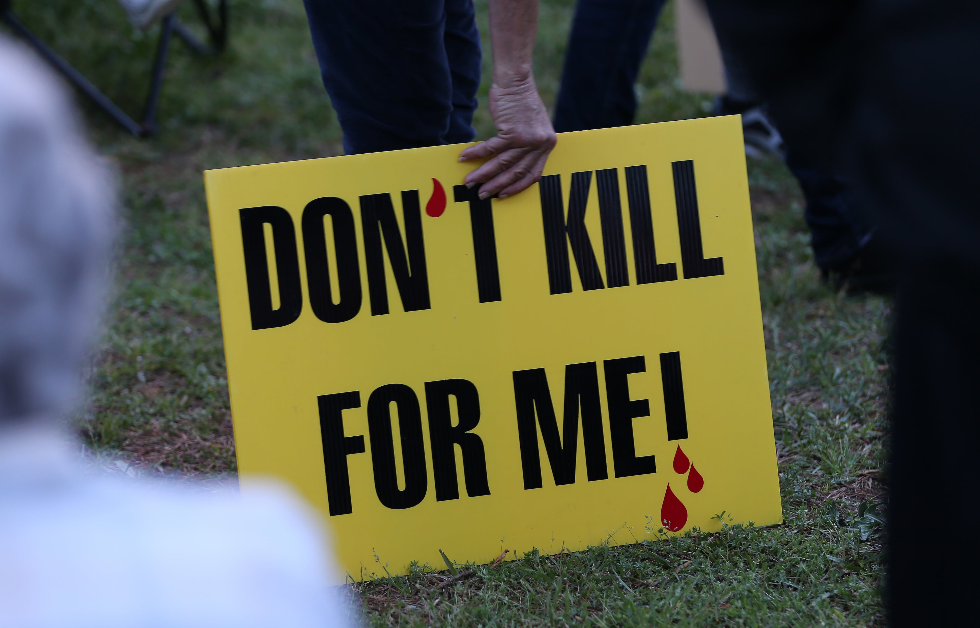 A death penalty opponent picks up her sign while protesting outside of the Georgia Diagnostic and Classification State Prison on March 31, 2016. Ben Gray / bgray@ajc.com