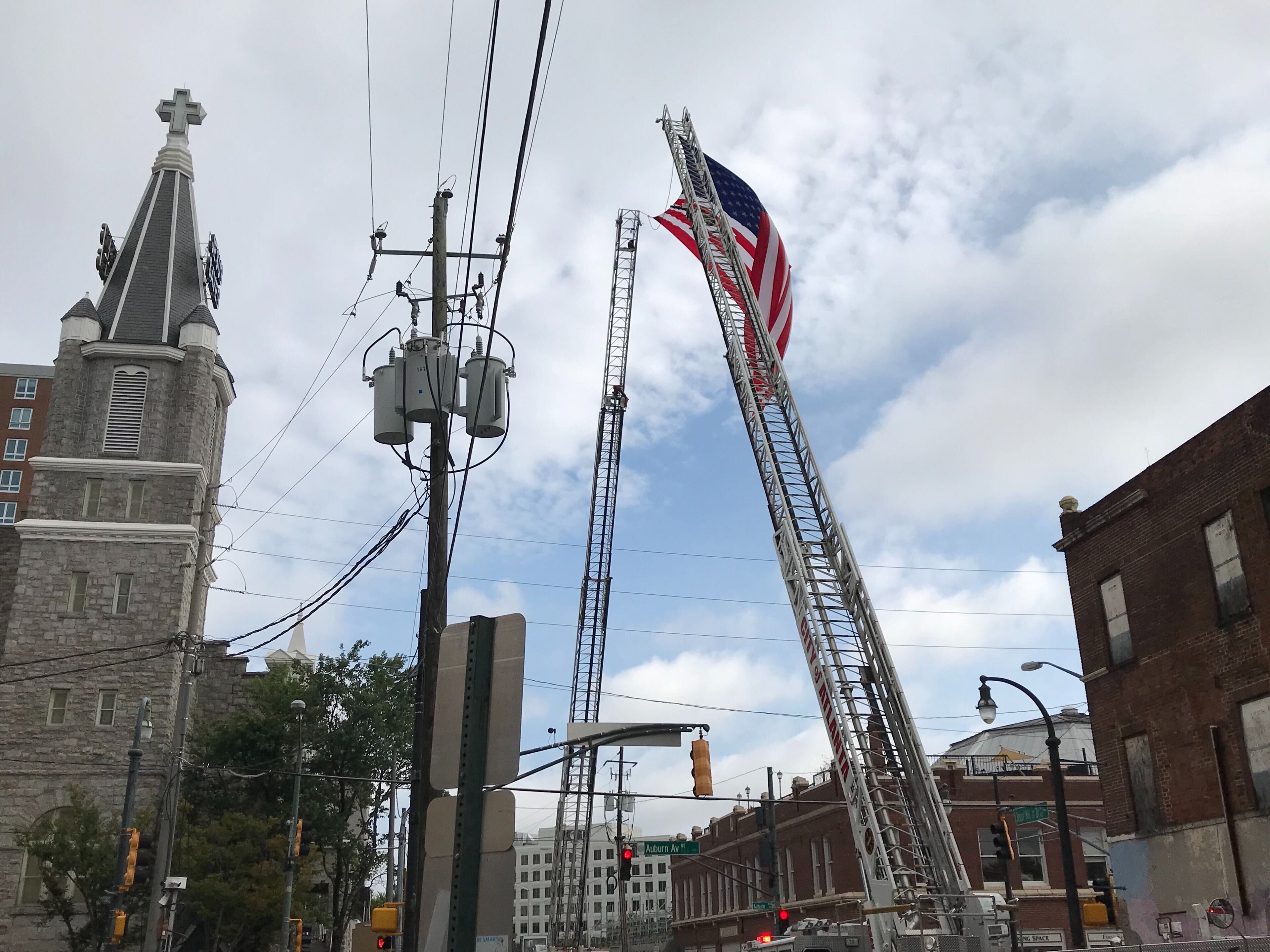 An American flag was hoisted above Auburn Avenue Thursday atop two fire truck ladders before the funeral of Congressman John Lewis. (Shelia Poole / AJC)