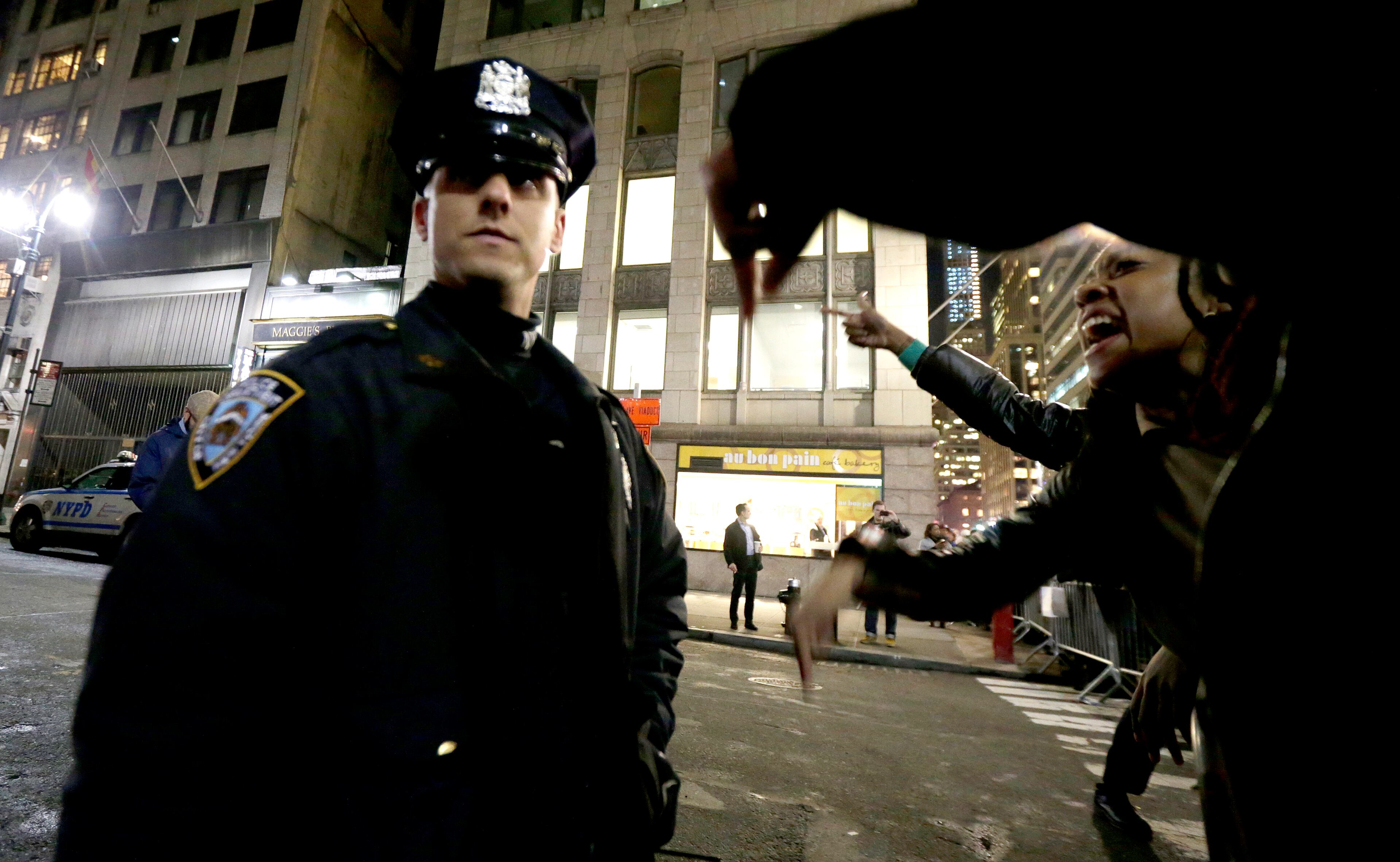 A woman, right, yells at a New York City Police officer during a protest after it was announced that the police officer involved in the death of Eric Garner is not being indicted, Wednesday, Dec. 3, 2014, in New York. A grand jury cleared the white New York City police officer Wednesday in the videotaped chokehold death of Garner, an unarmed black man, who had been stopped on suspicion of selling loose, untaxed cigarettes, a lawyer for the victim's family said. A video shot by an onlooker and widely viewed on the Internet showed the 43-year-old Garner telling a group of police officers to leave him alone as they tried to arrest him. The city medical examiner ruled Garner's death a homicide and found that a chokehold contributed to it. (AP Photo/Julio Cortez)
