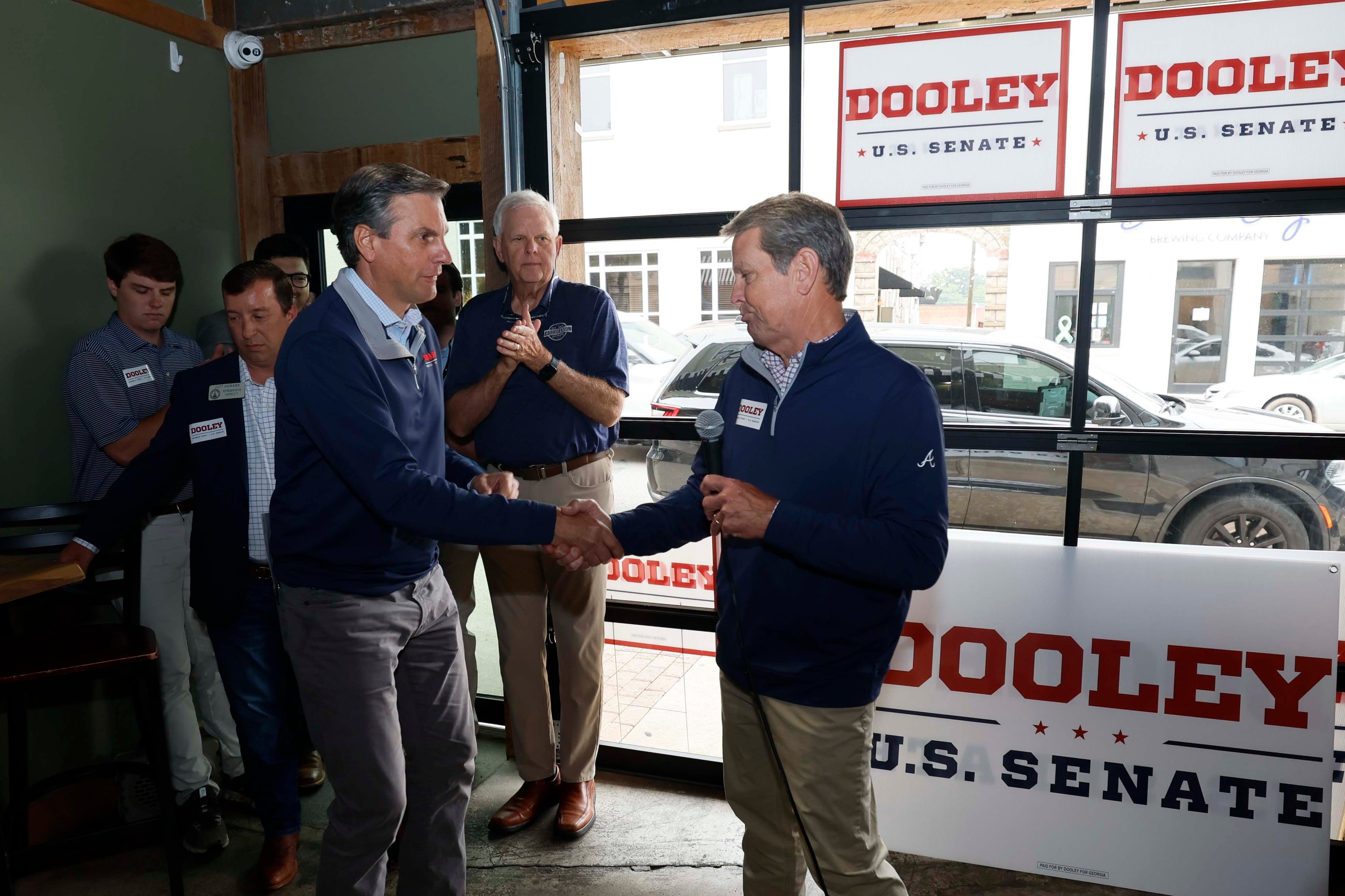 Gov. Brian Kemp (right) welcomes U.S. Senate hopeful Derek Dooley during a campaign event in downtown Carrollton on Monday. (Miguel Martinez/AJC)