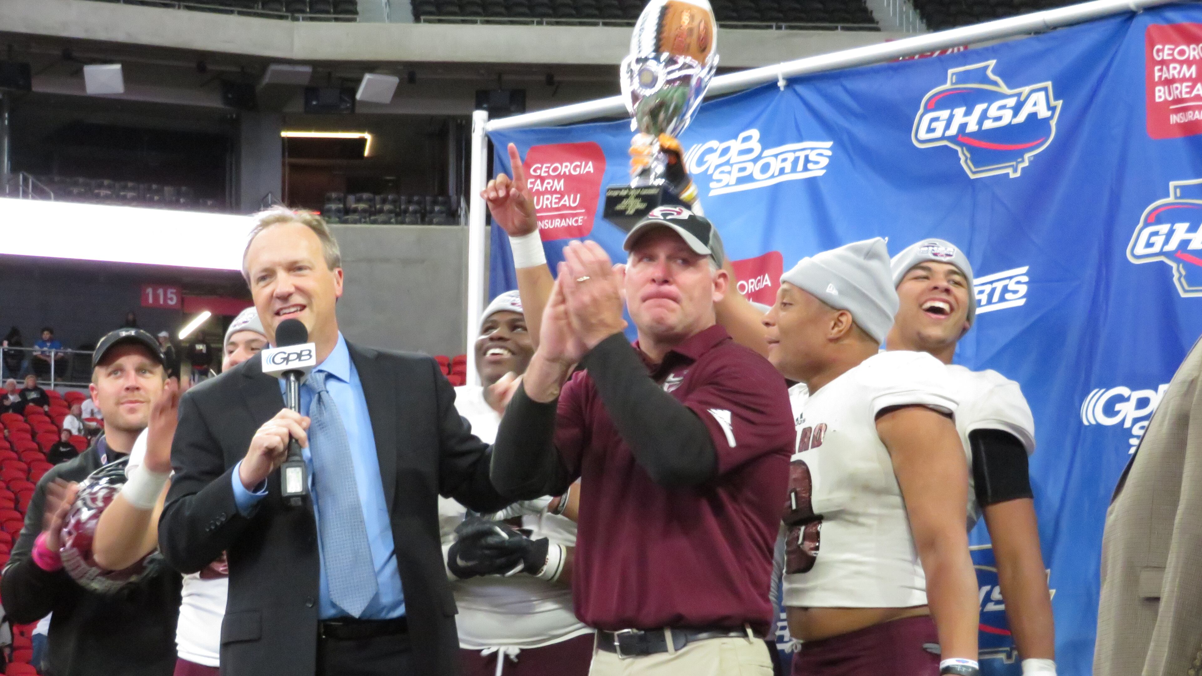 Heard County Braves coach Tim Barron claps as his players hoist the Class AA state championship trophy following their 27-6 win over the Rockmart Yellow Jackets on Wednesday, Dec. 12, 2018 at Mercedes-Benz Stadium.