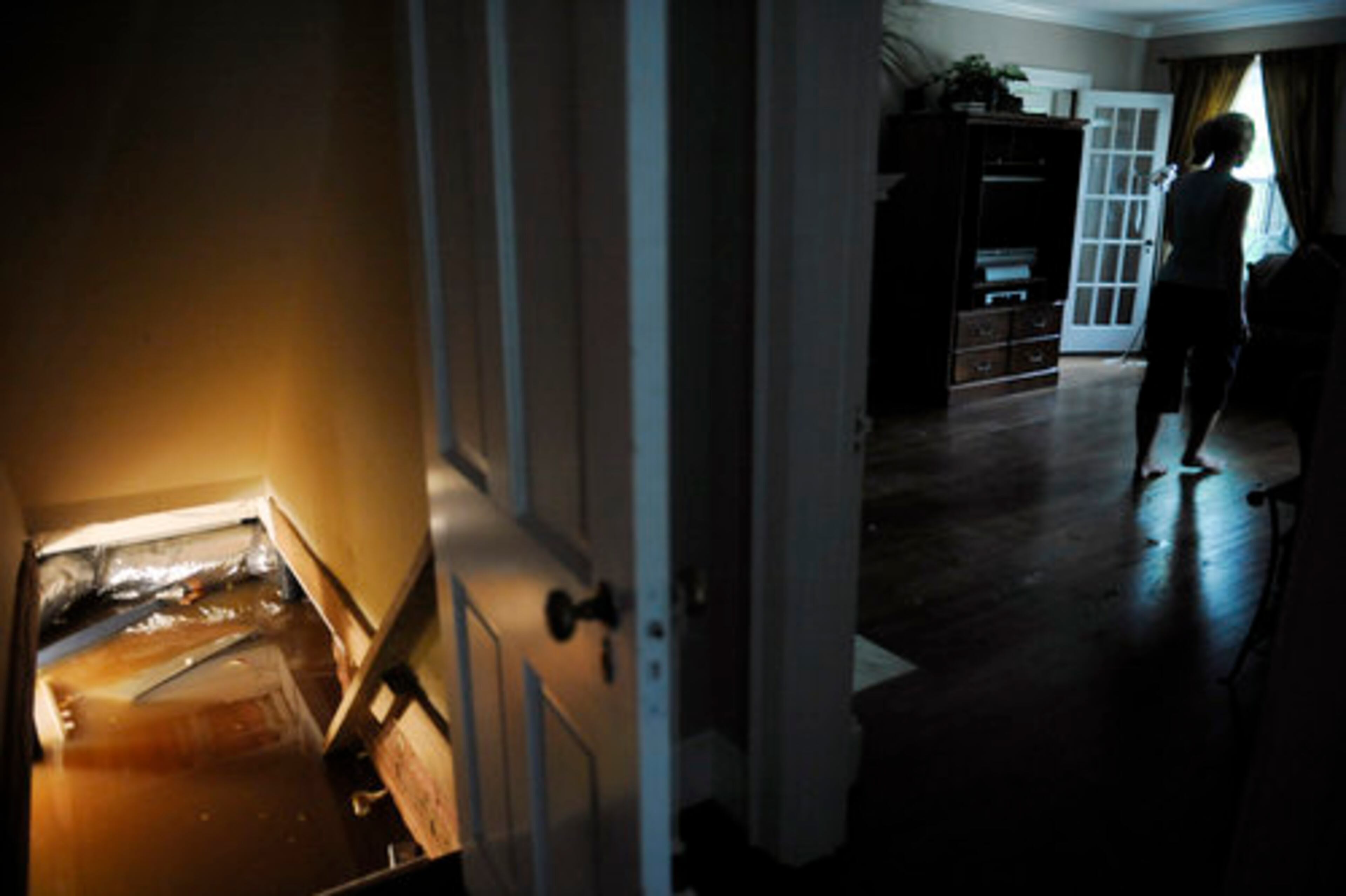 Cathrine Nelke, 43, walks through the main level of her home past her basement that is flooding due to an overflowing Peachtree Creek and a broken water main on Woodward Way in Atlanta. Eventually, a neighbor stopped the water from the broken main from rushing into her home.