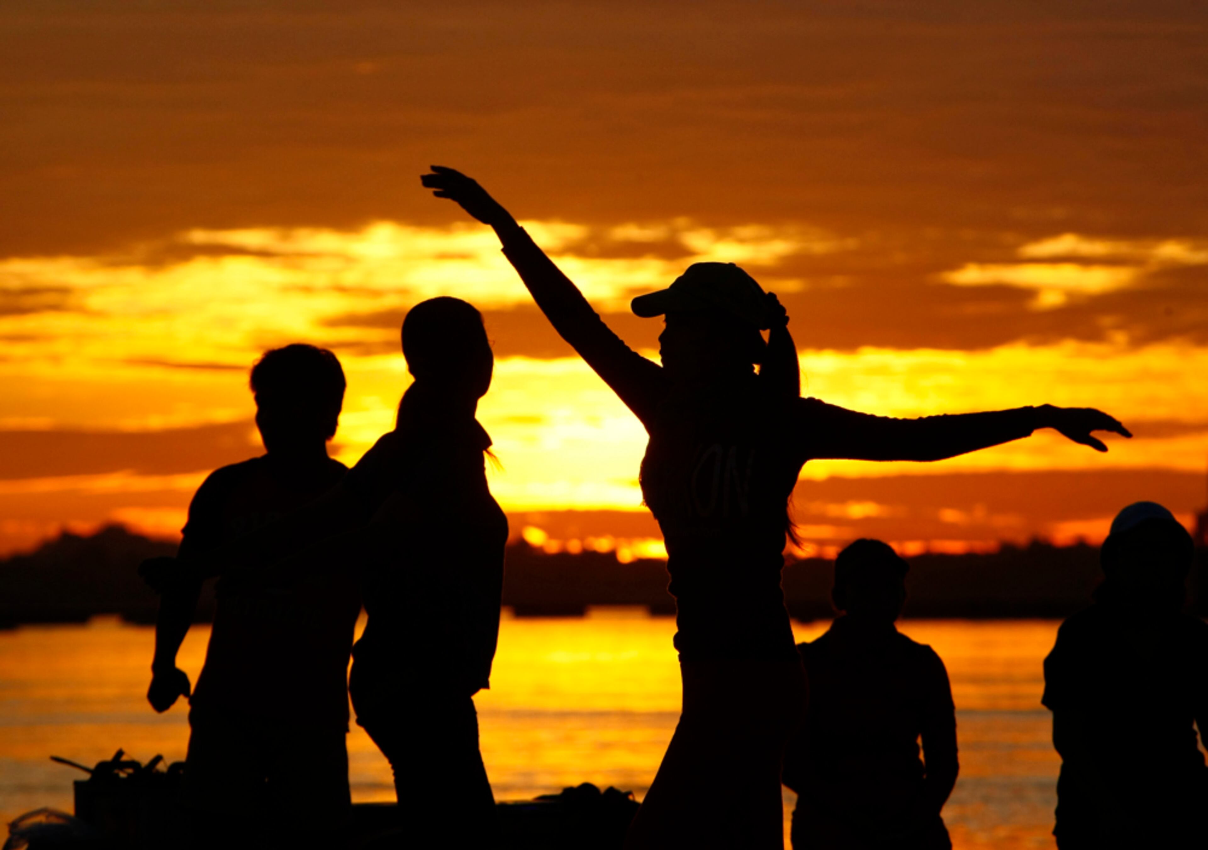 STRETCHING AT SUNRISE--Residents take their morning exercise at the bank of the Tonle Sap river near the Royal Palace, in Phnom Penh, Cambodia, Friday, Aug. 8, 2014. (AP Photo/Heng Sinith)