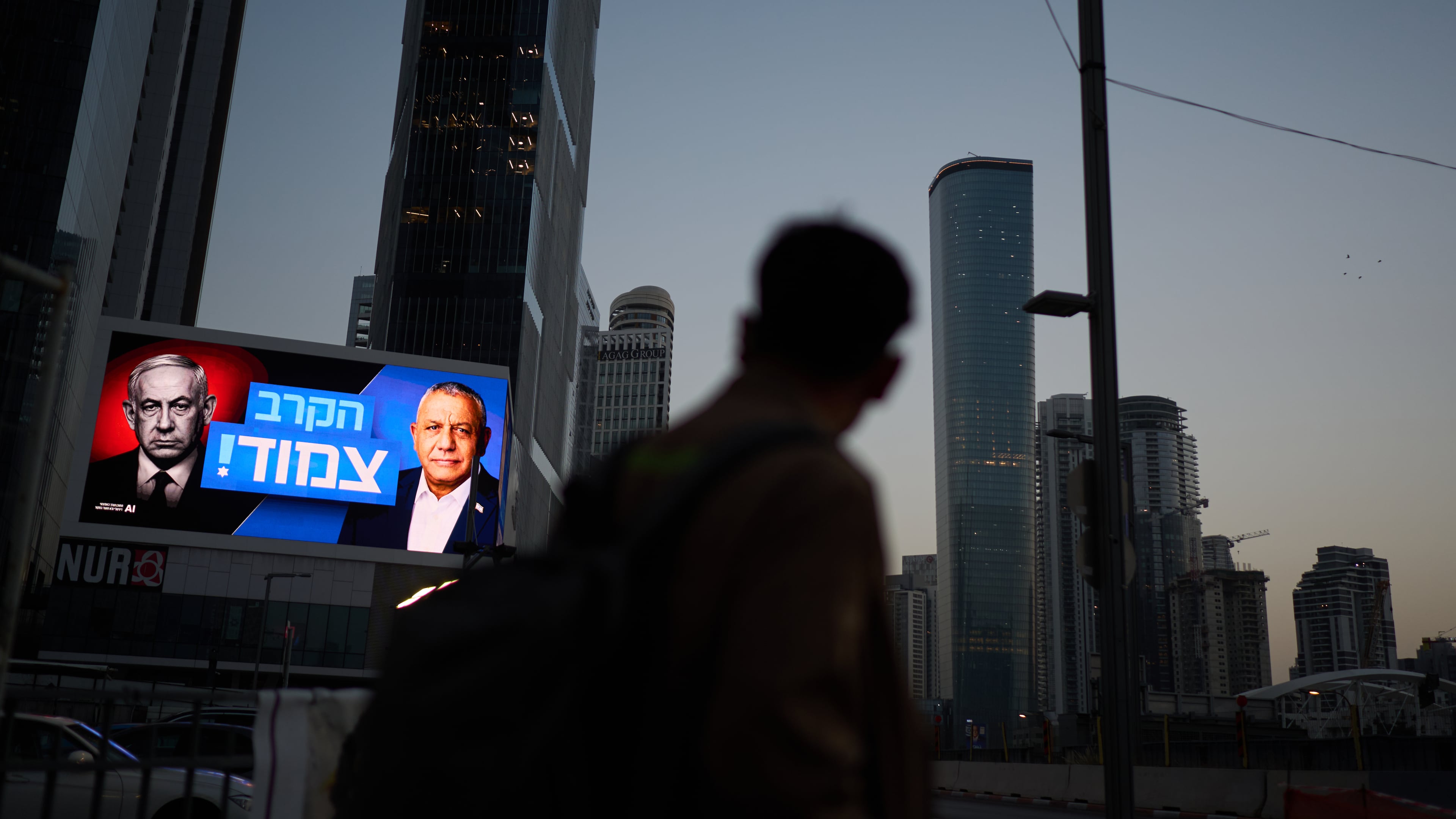 A pedestrian passes a campaign billboard featuring Israeli Prime Minister Benjamin Netanyahu, left, and his main rival, opposition candidate Gadi Eisenkot, with a message in Hebrew that reads "The race is tight," Friday, Oct. 23, 2026, in Tel Aviv, Israel. (AP Photo/David Goldman)