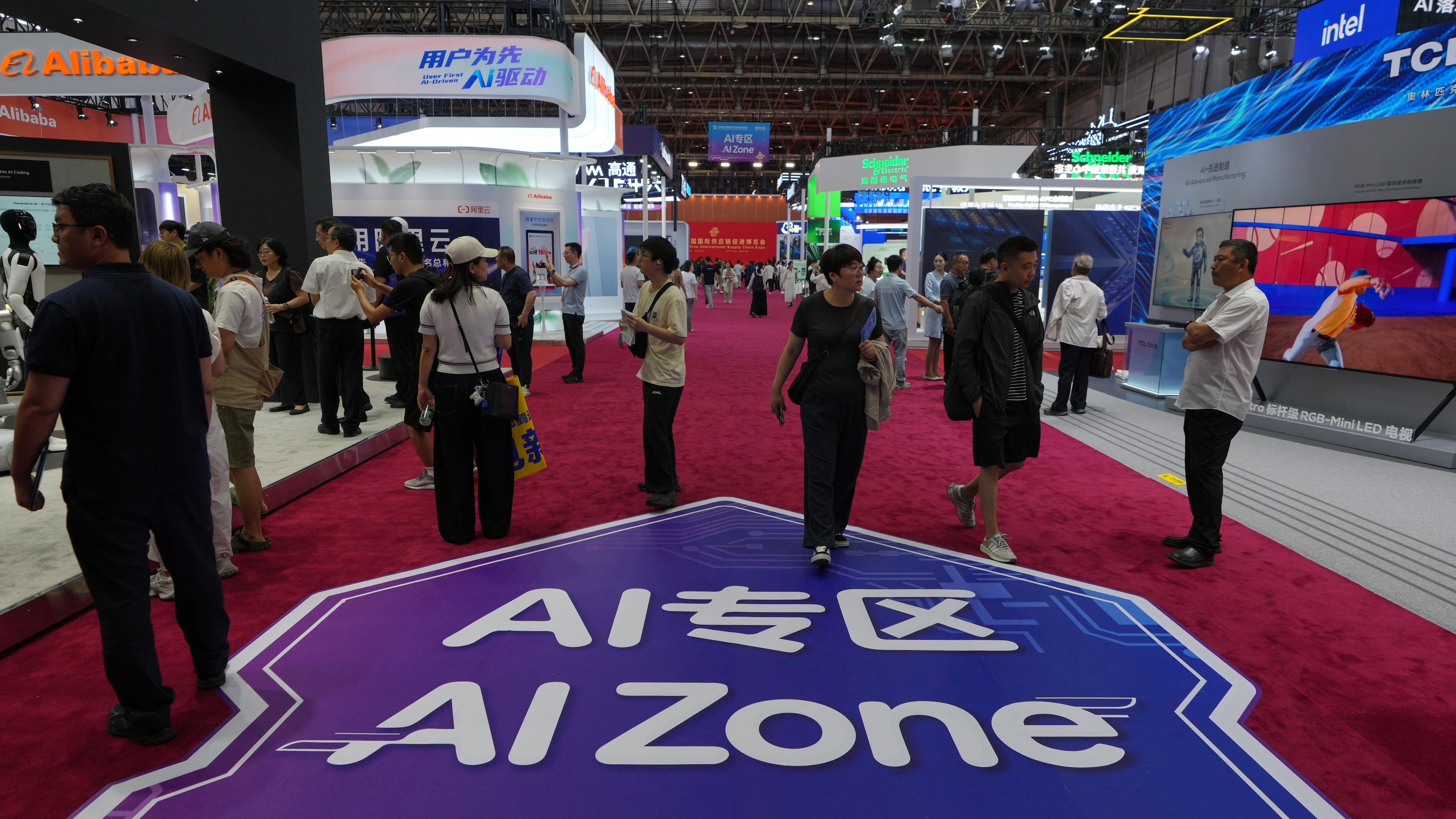 Visitors tour exhibition booths operated with artificial intelligence at the China International Supply Chain Expo in Beijing in June. (Andy Wong/AP)