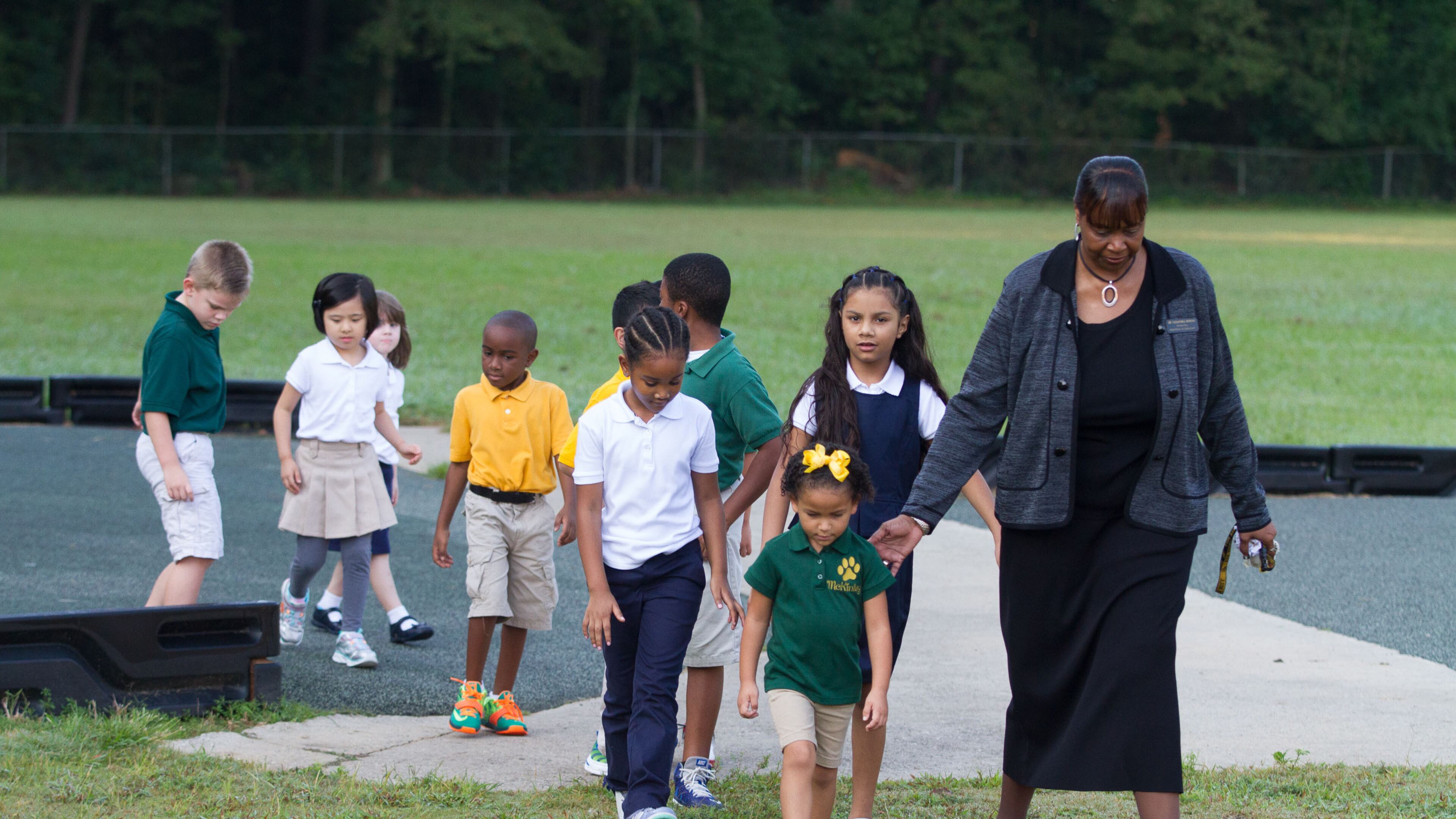 Elementary school principal Dr. Cassandra Hopkins leads the students in from the playground after a portrait session about school uniforms Wednesday, August 2, 2015, at McGarrah Elementary School in Morrow, GA. STEVE SCHAEFER / SPECIAL TO THE AJC