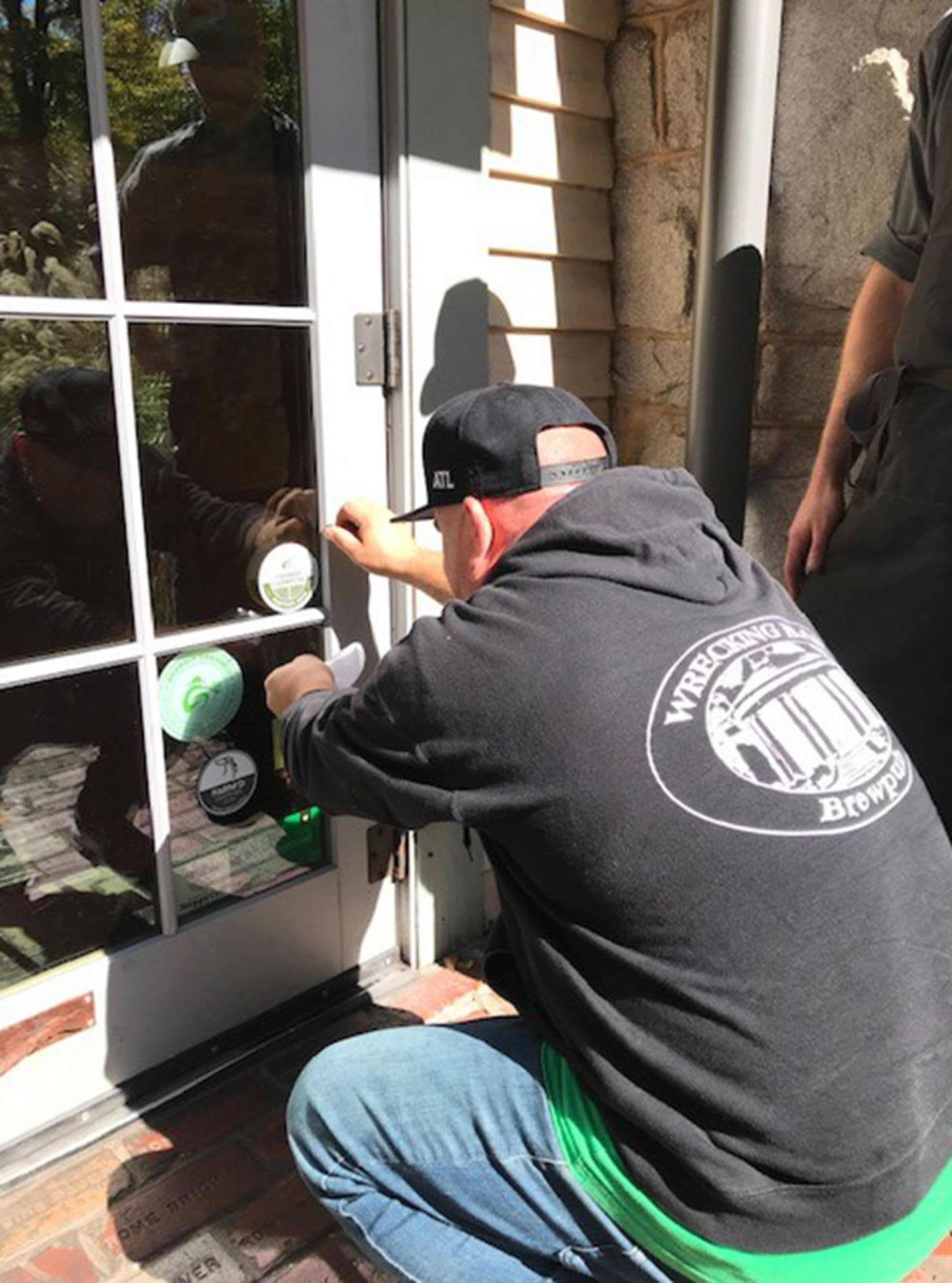 A member of the Wrecking Bar team applies a Farmer Champion decal to the restaurant's door.