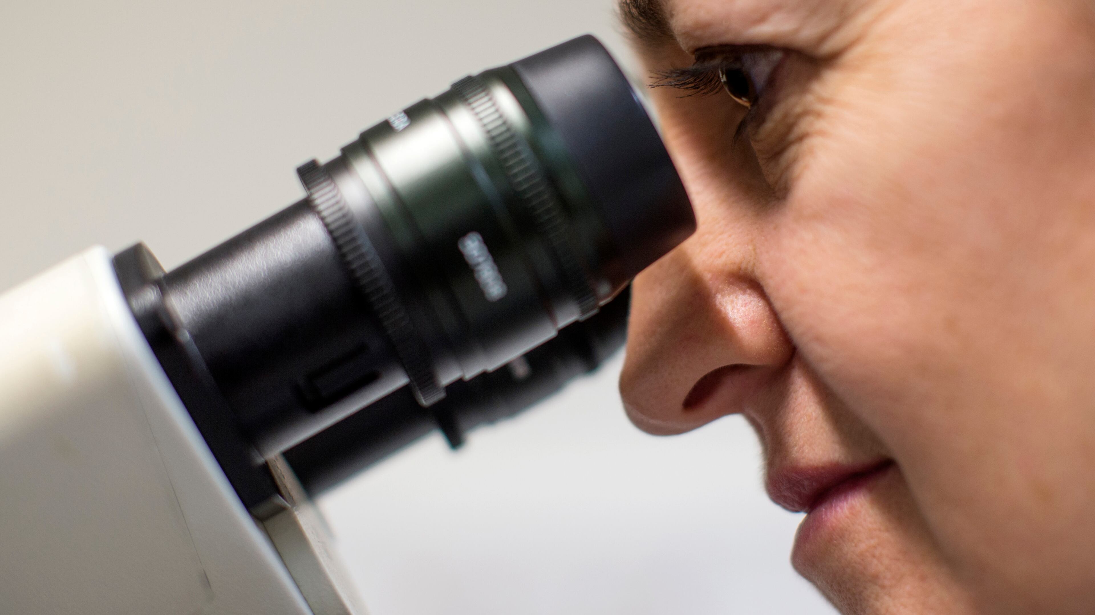 A Scientist looks at cells through a fluorescent microscope.