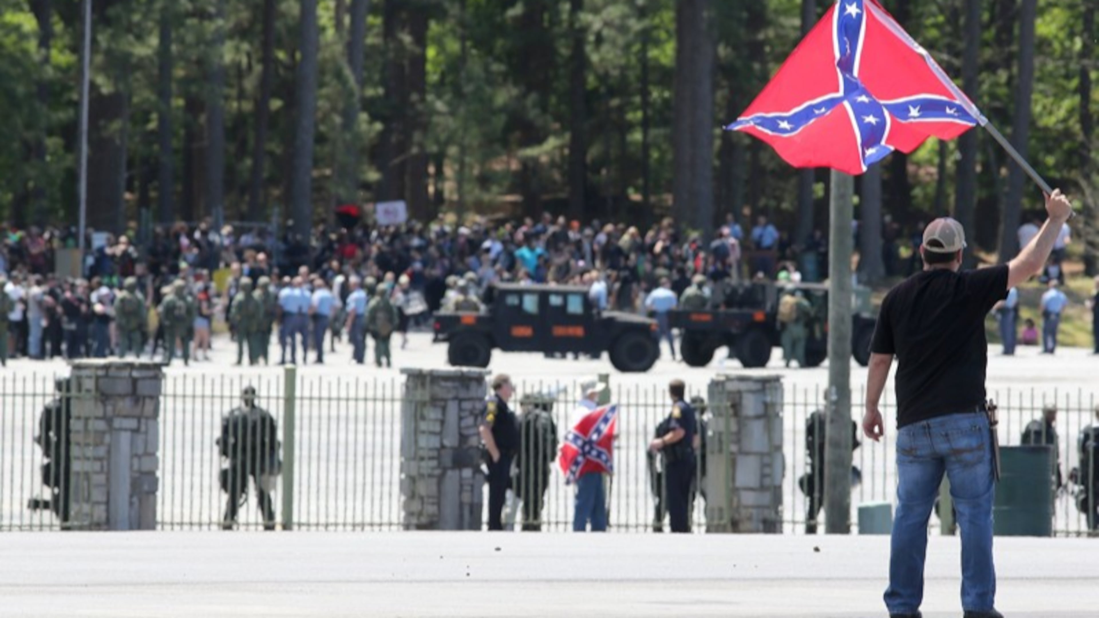 Joseph Andrews, one of a small group with the Rock Stone Mountain rally, waves a confederate battle flag towards a mass of counter-protesters more than 100 yards away at Stone Mountain Park on Saturday afternoon April 23, 2016 where a white power protest and two counter protests were scheduled.