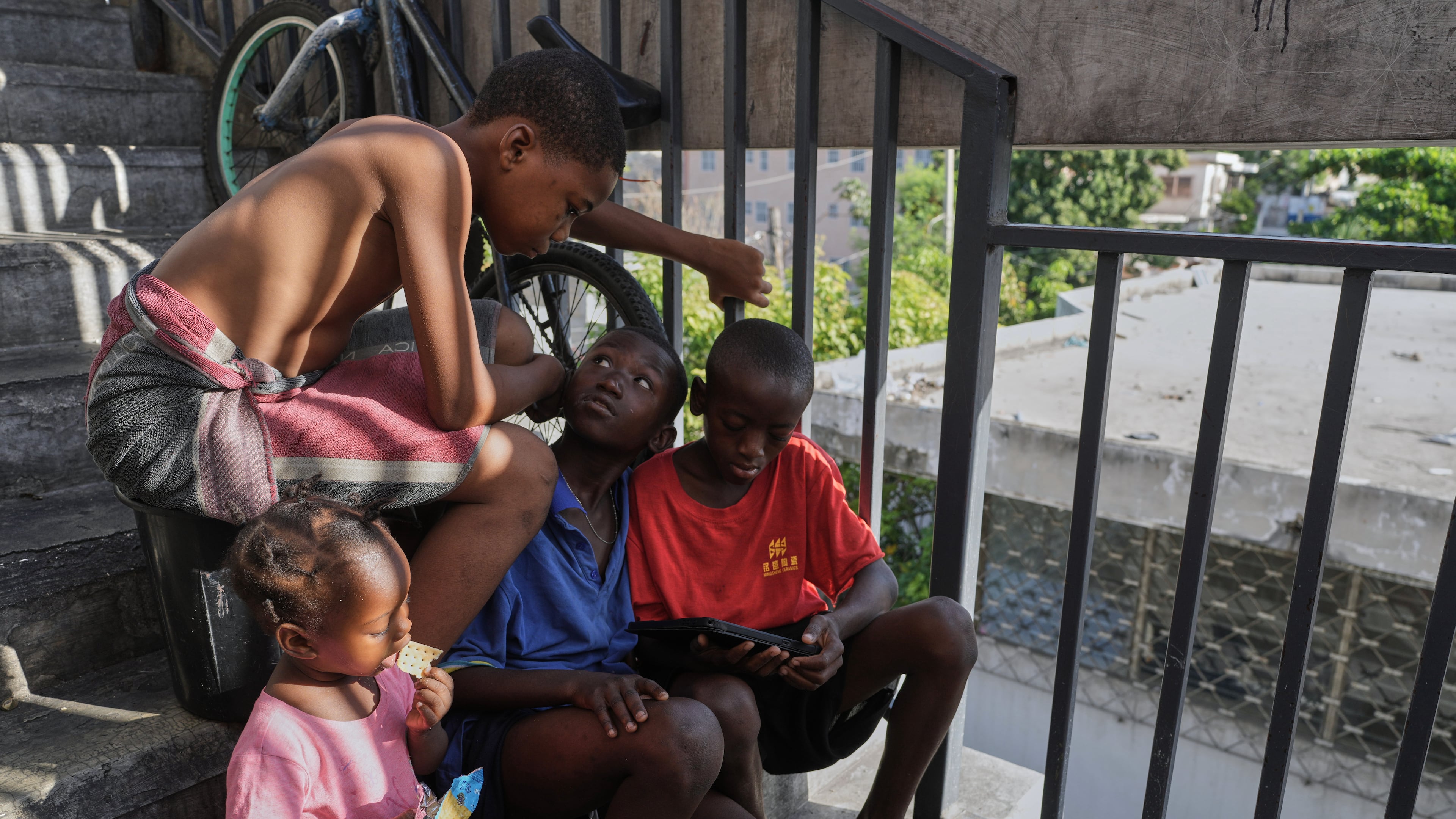 Children watch a movie on a mobile device at a shelter for families displaced by gang violence in Port-au-Prince, Haiti, Wednesday, Aug. 19, 2026. (AP Photo/Odelyn Joseph)