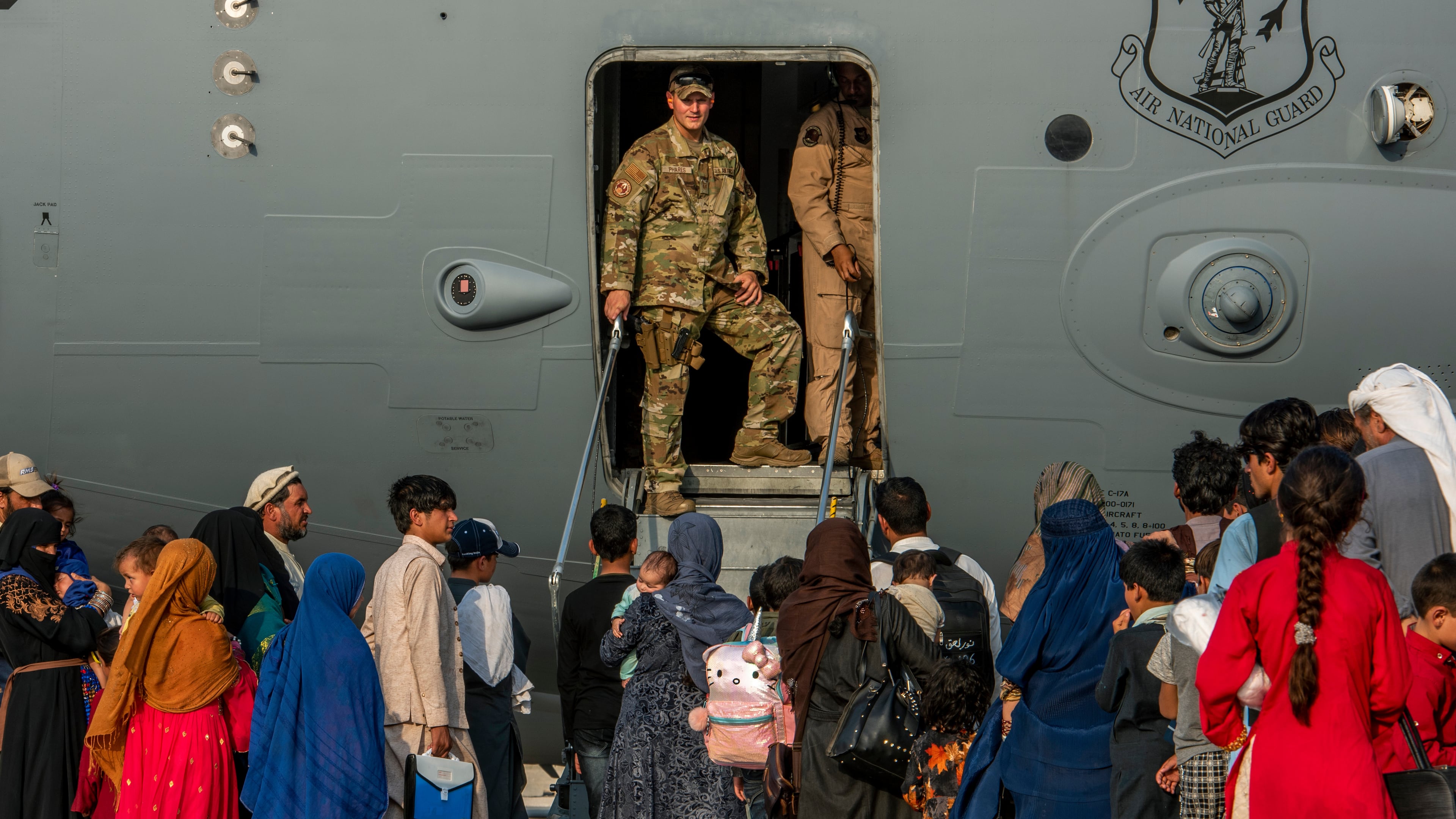 FILE - In this Aug. 22, 2021 file photo provided by the U.S. Air Force, service members stand at a doorway as Afghan evacuees prepare to board an aircraft, Aug. 22, 2021, at Al Udeid Air Base, Qatar. (Airman 1st Class Kylie Barrow/U.S. Air Force via AP, File)