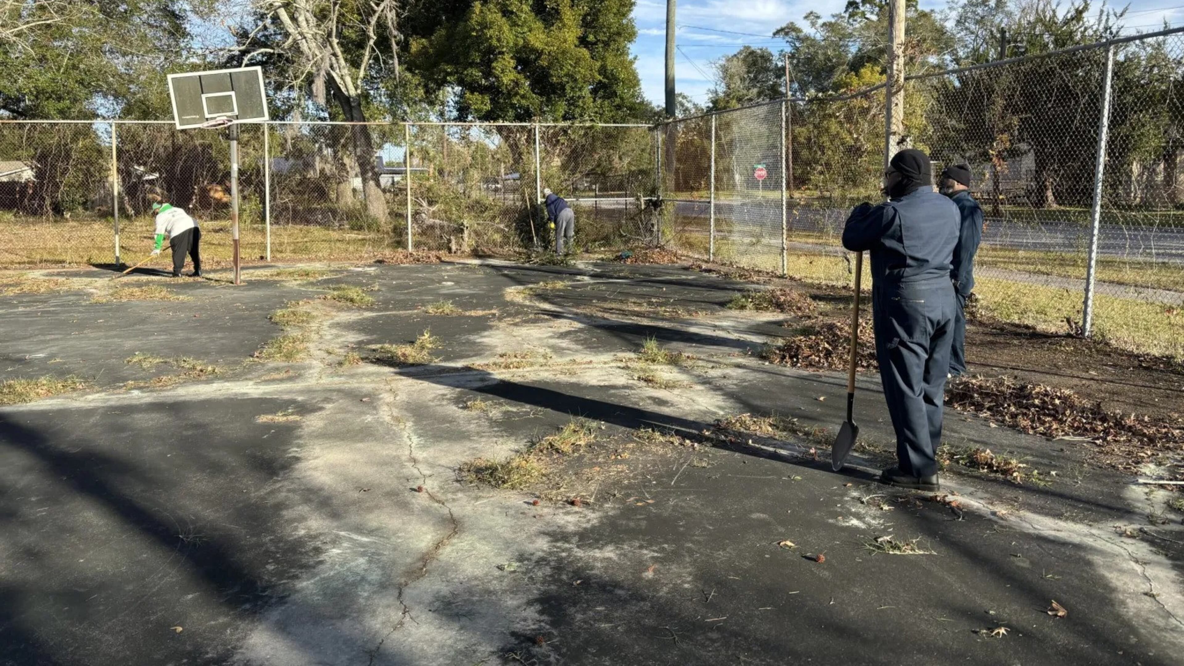 Volunteers uproot overgrown weeds in the cracked concrete of the basketball courts at New Glory Christian Center in Brunswick on Saturday, Jan. 13, 2024. The effort was part of a community workday organized by A Better Glynn, Forward Brunswick and United Way of Coastal Georgia over Dr. Martin Luther King Jr. Day weekend. (Photo Courtesy of Jake Shore/The Current)