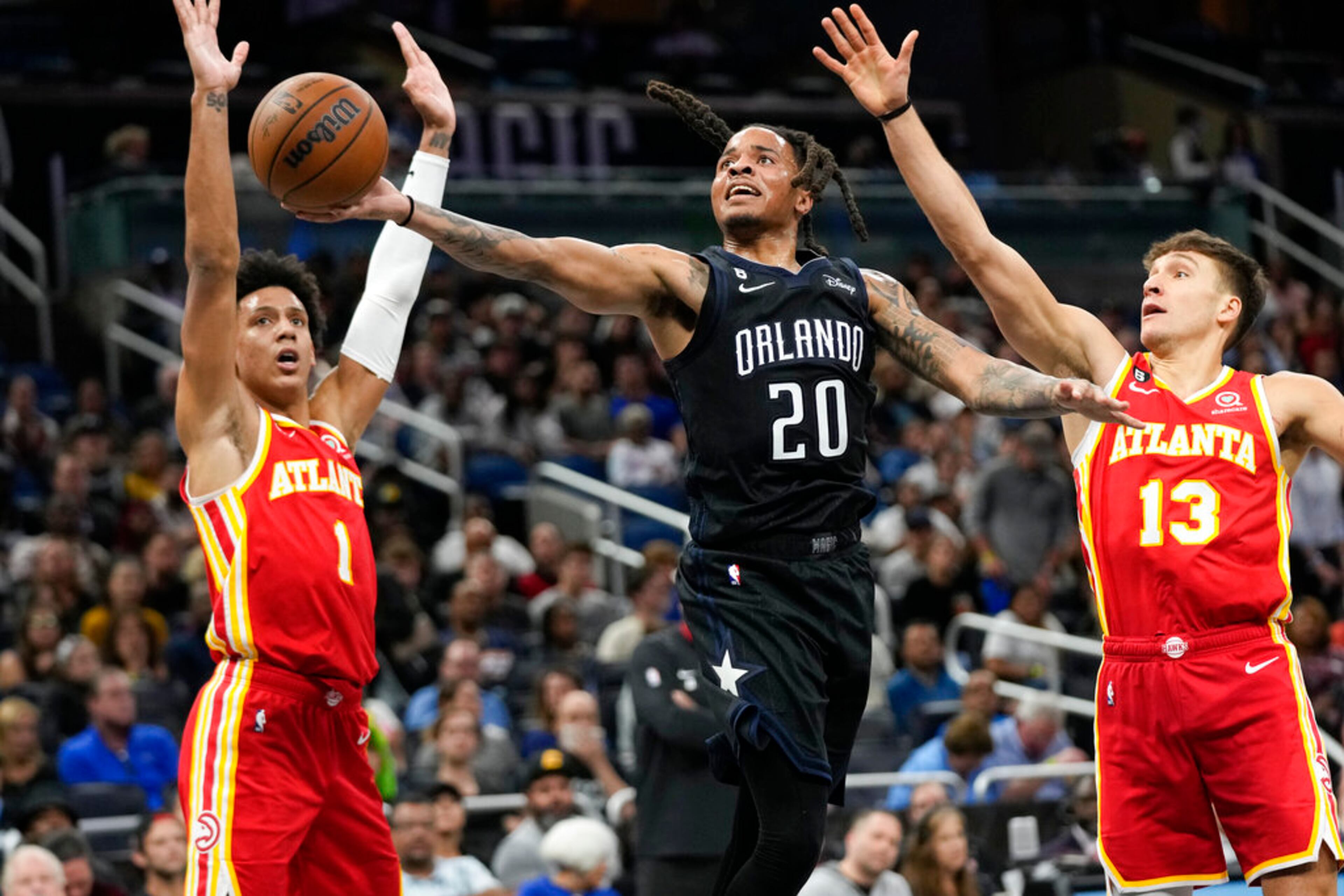 Orlando Magic's Markelle Fultz (20) gets off a shot between Atlanta Hawks' Jalen Johnson (1) and Bogdan Bogdanovic (13) during the second half of an NBA basketball game, Wednesday, Dec. 14, 2022, in Orlando, Fla. (AP Photo/John Raoux)