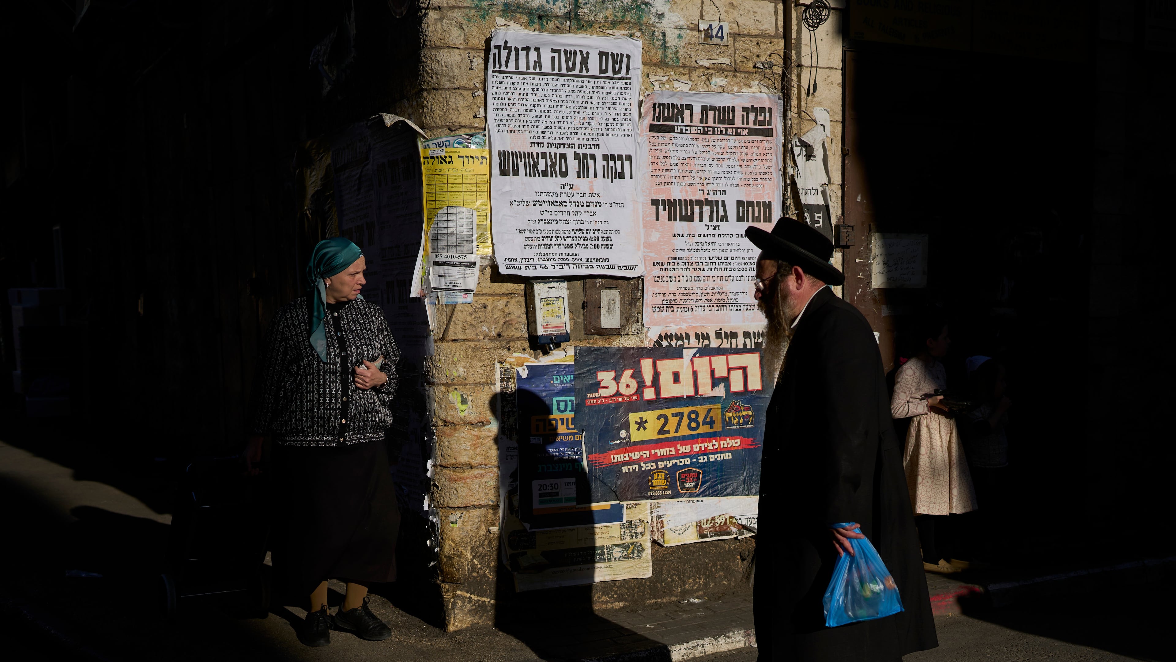 Ultra-Orthodox Jews walks past pashkevilim, posters used to publicize news and important messages in the ultra-Orthodox community, in the Mea Shearim neighborhood of Jerusalem, Wednesday, July 8, 2026. (AP Photo/Ohad Zwigenberg)