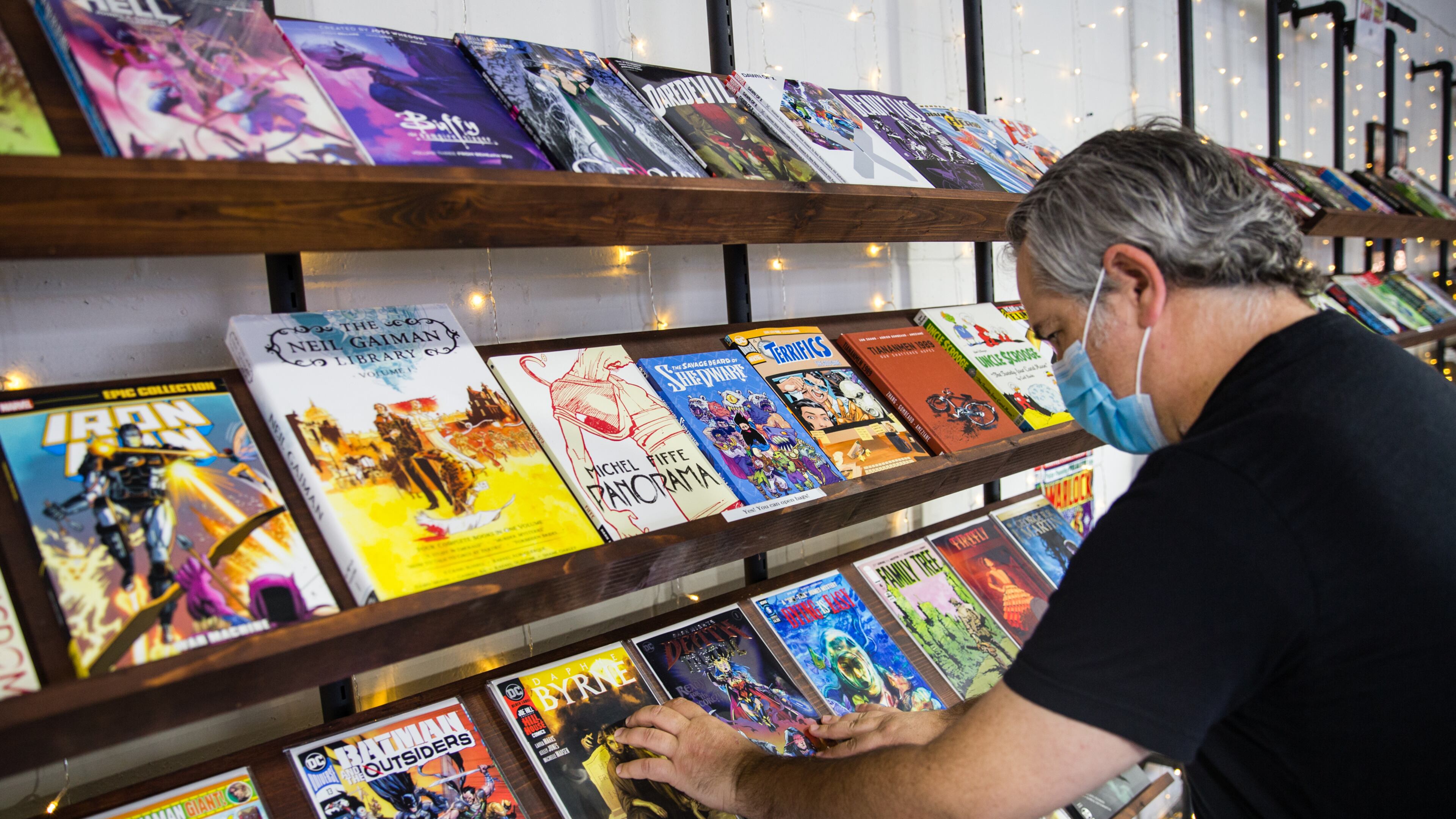 Infinite Realities co-owner Chris Brennaman organizes the weekly new releases in Tucker where the comic book store is open for business again and providing comics to loyal, local customers with COVID-19 protections. Jenni Girtman for The AJC